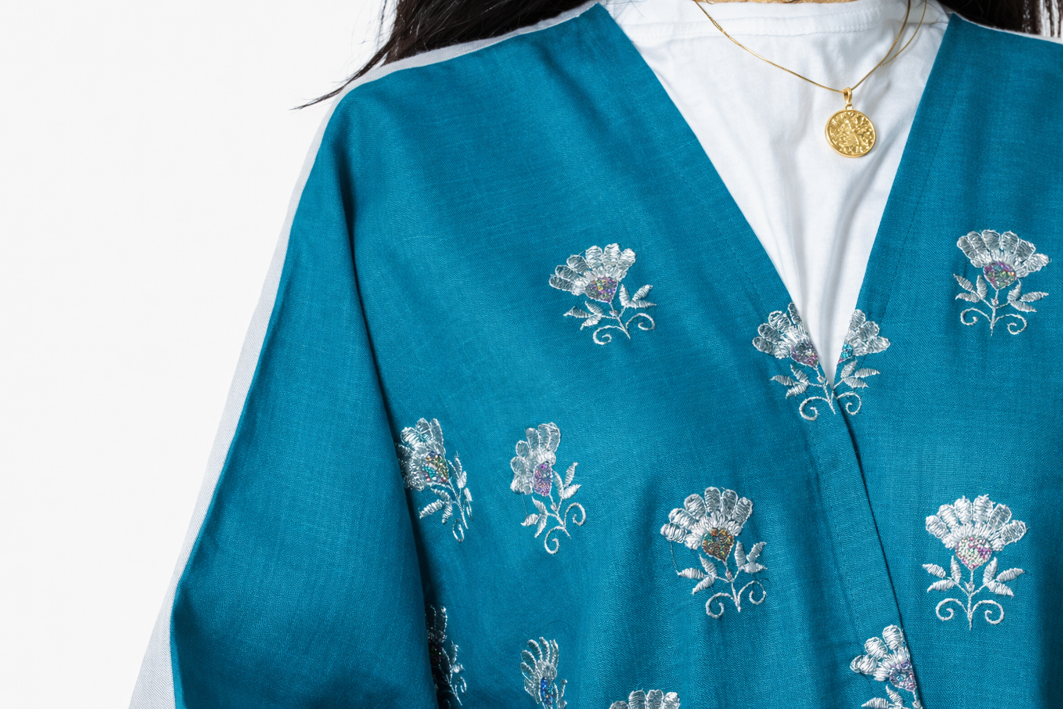 Teal cardigan with floral embroidery on a white background