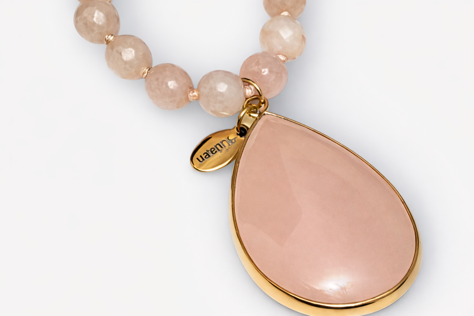 Necklace with pink teardrop pendant and gold accents on a white background