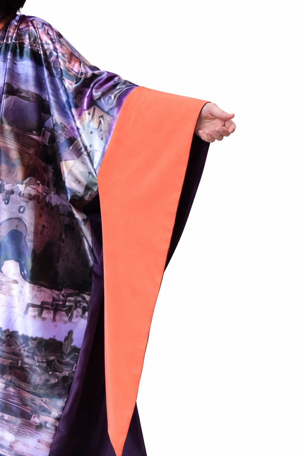 Colorful scarf with abstract patterns and an orange strip held by a hand on a white background