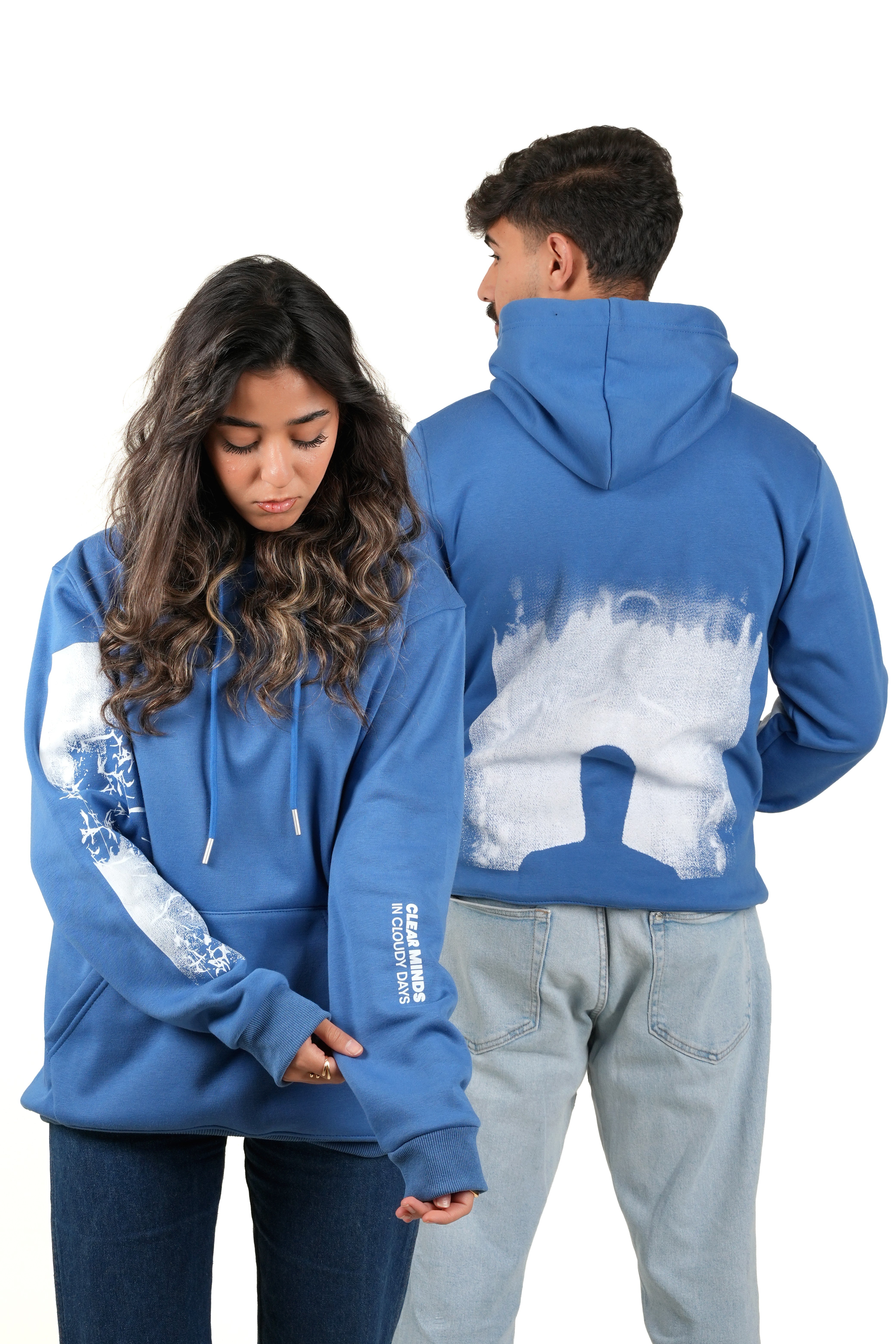 Two people wearing blue hoodies with a white graphic design on a white background