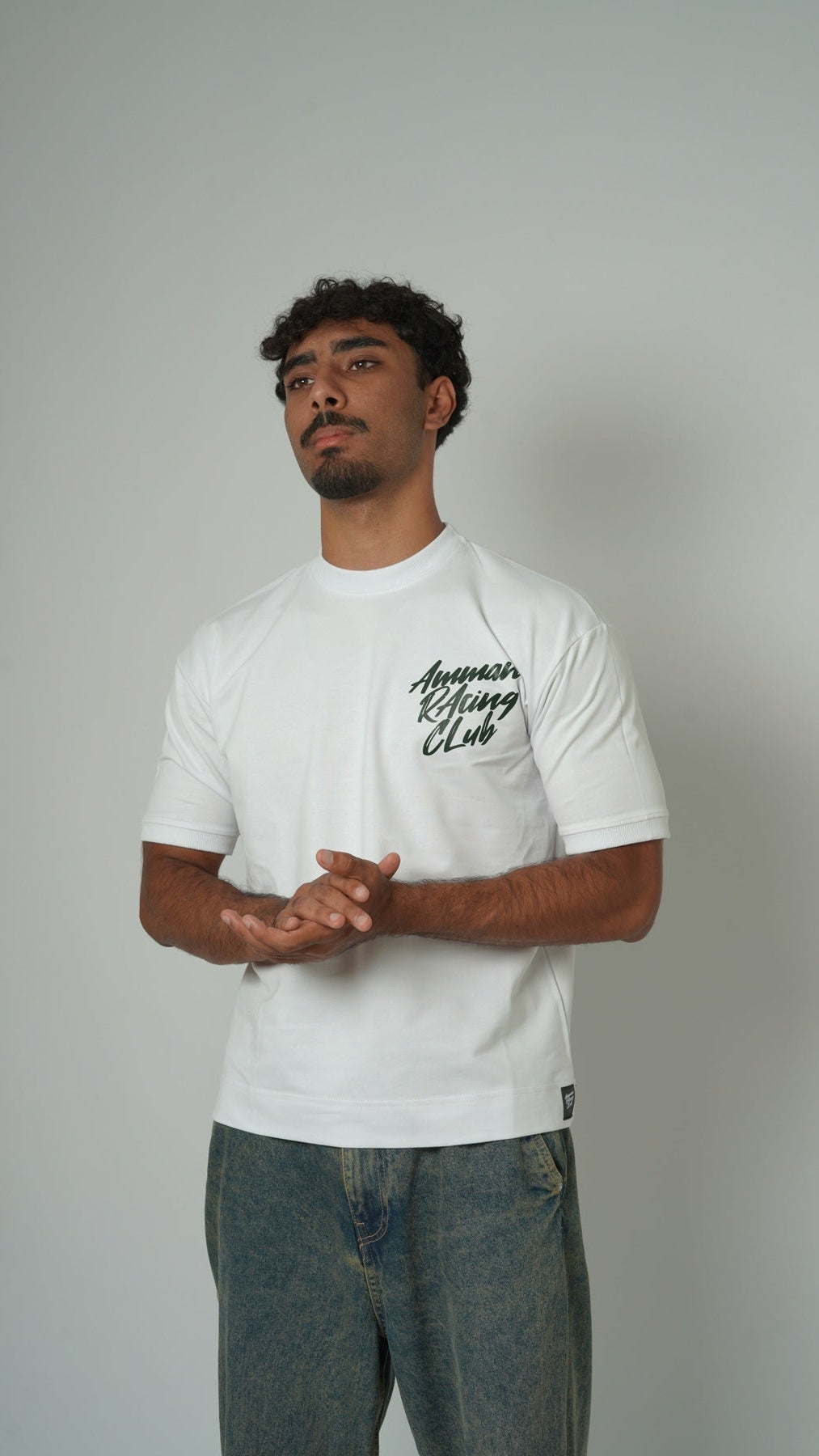 Man wearing a white t-shirt with text on a plain background