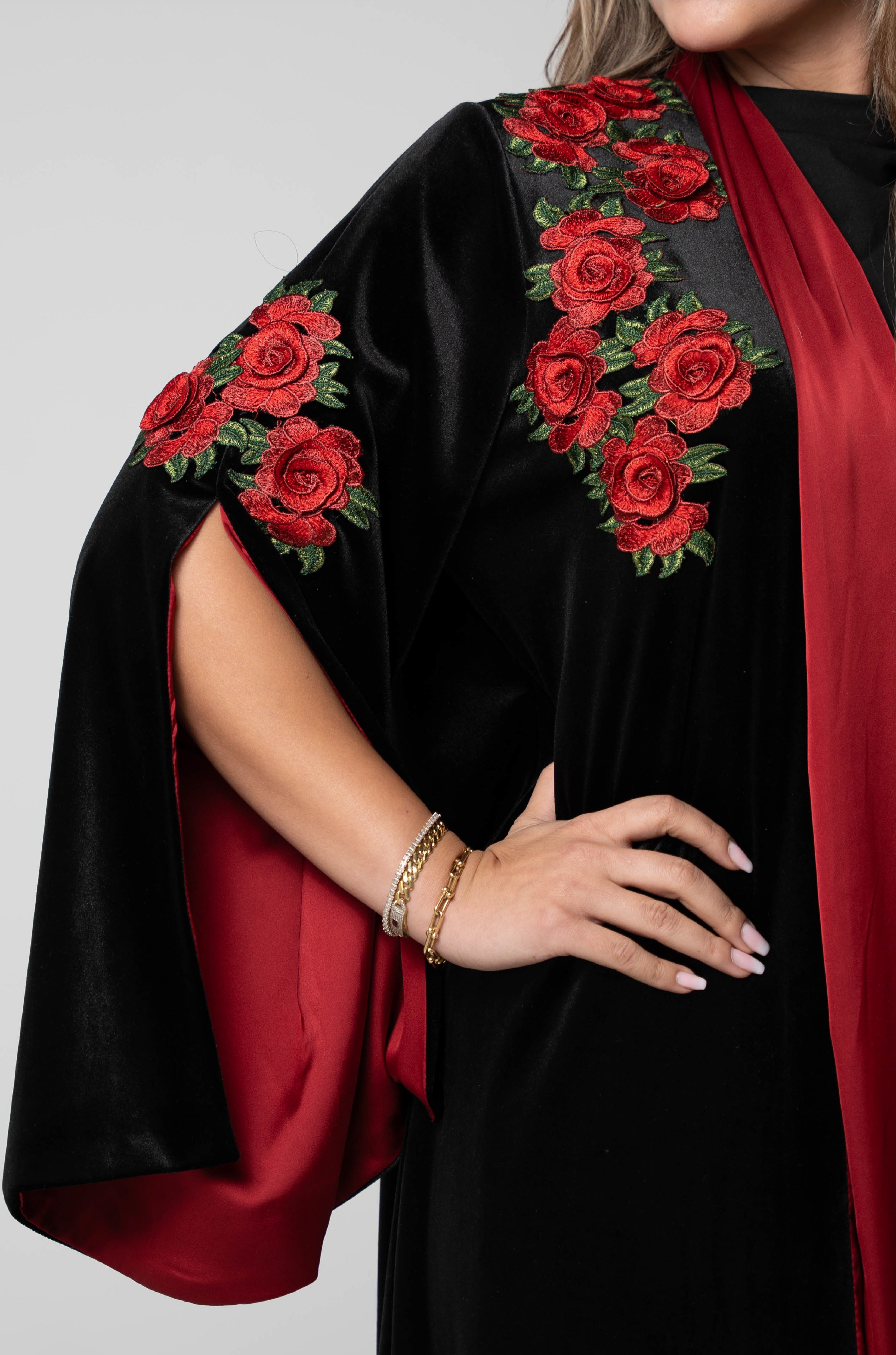 Black garment with red floral embroidery on a plain background
