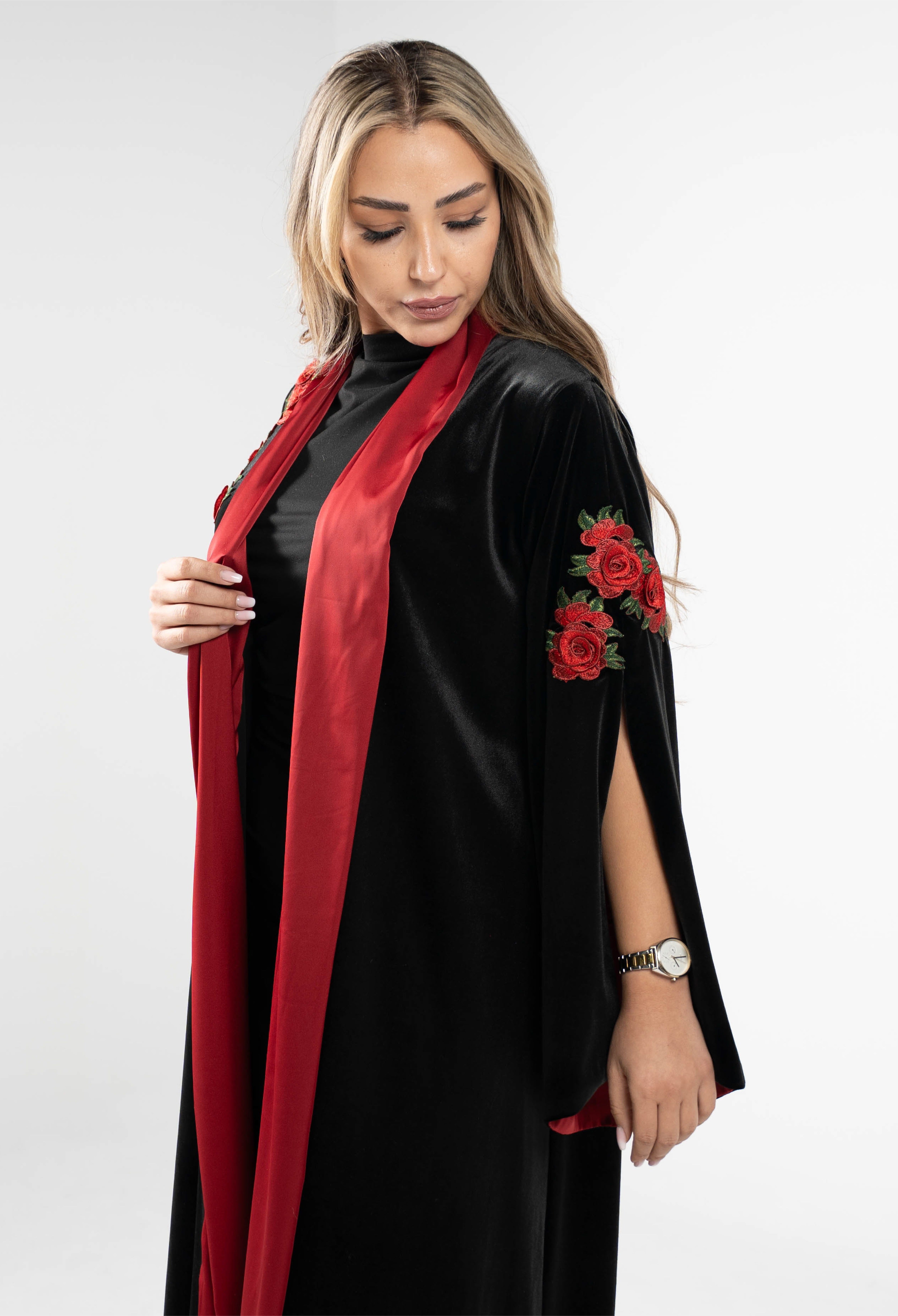 Woman wearing a black outfit with red accents and floral designs on a white background
