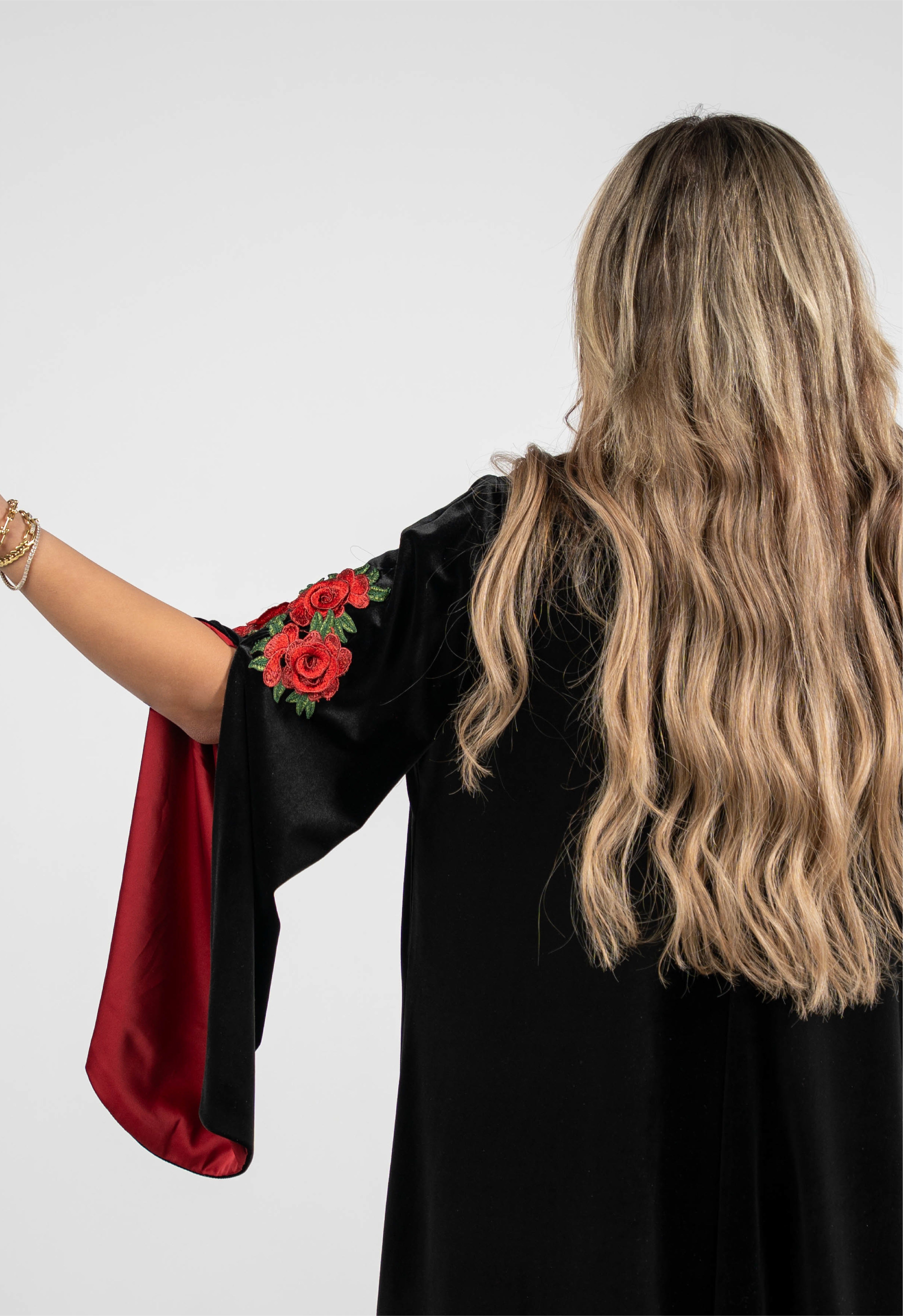Woman wearing a black dress with red sleeves featuring floral designs on a white background