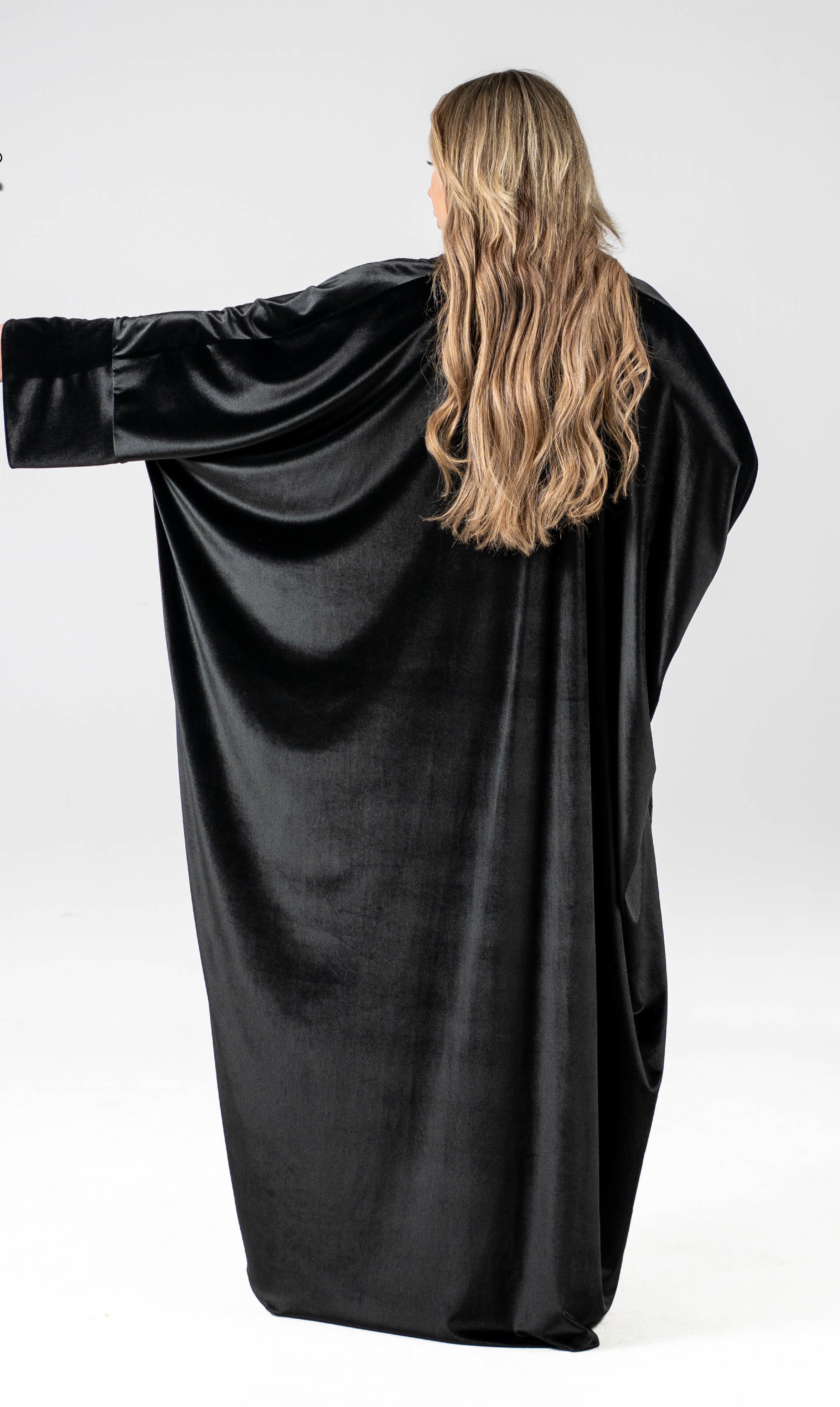 Person wearing a black velvet dress with long sleeves on a white background