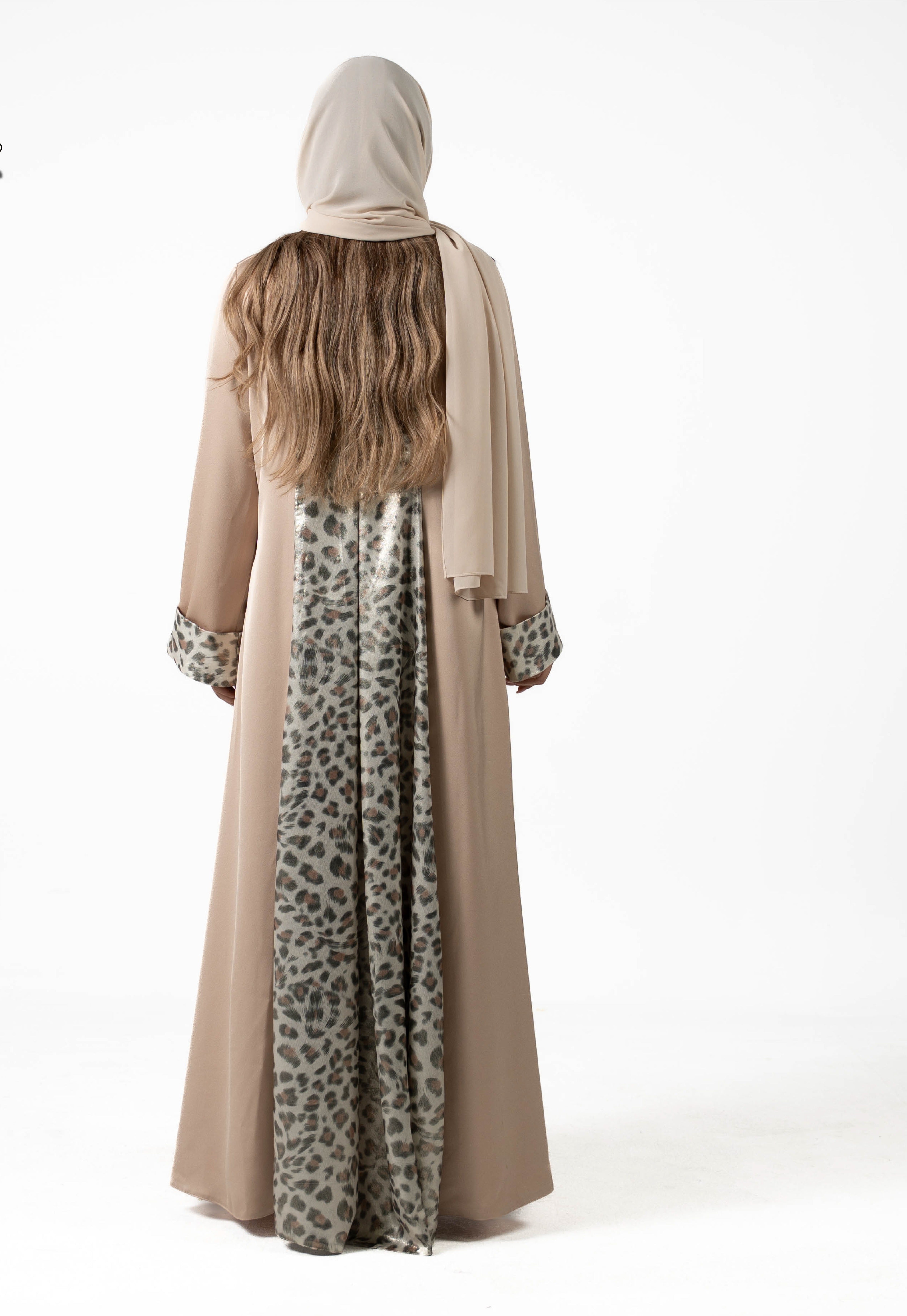 Person wearing a beige hijab and a long dress with a leopard print pattern on a white background