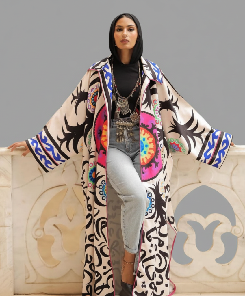 Woman wearing a colorful patterned coat standing against a gray background