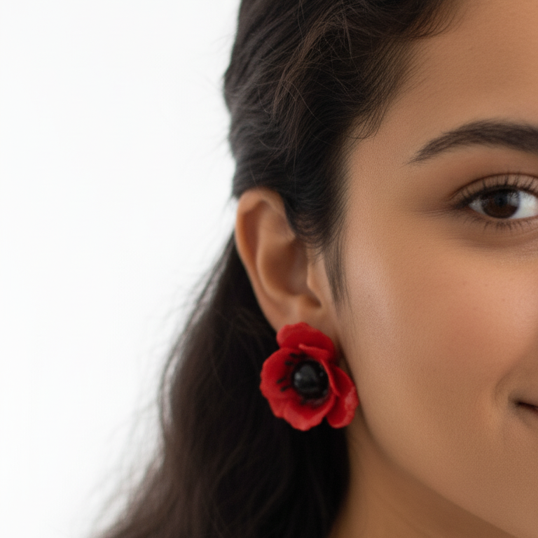 Close-up of a person wearing a red flower-shaped earring on a white background