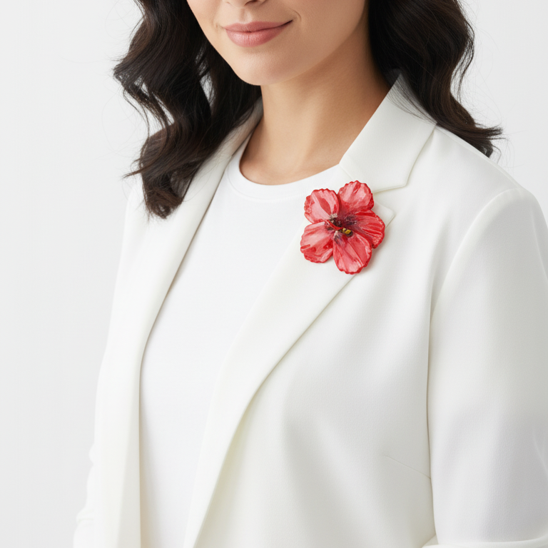 Woman wearing a white blazer with a red floral brooch on a white background