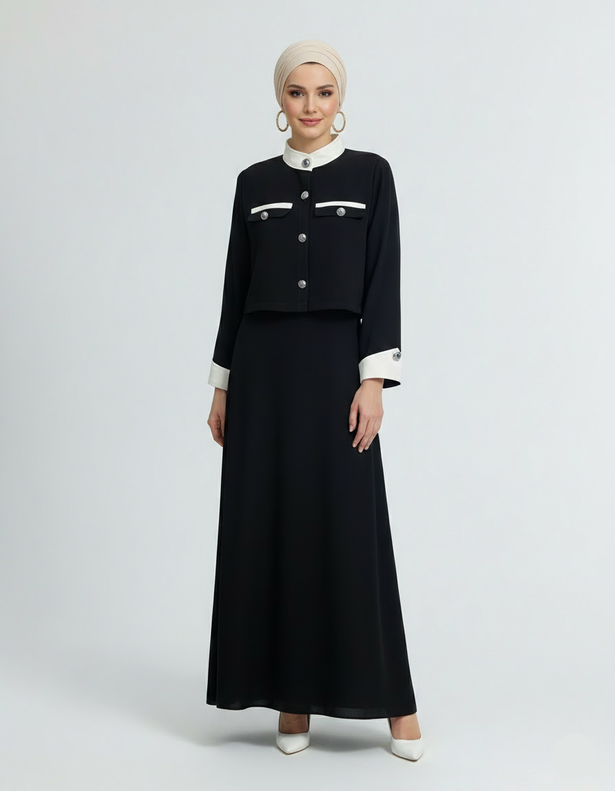 Woman wearing a black outfit with white accents on a light gray background