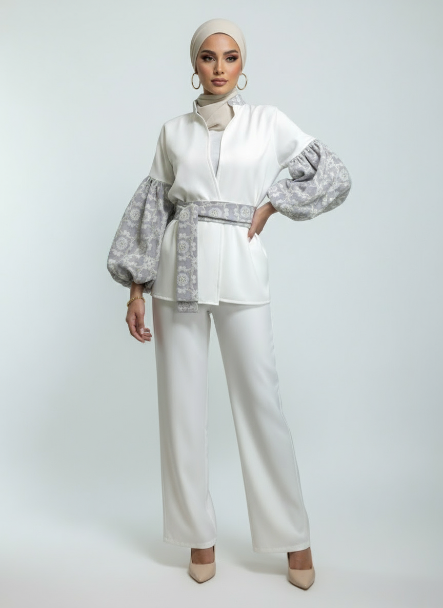 Woman wearing a white outfit with patterned sleeves on a light gray background