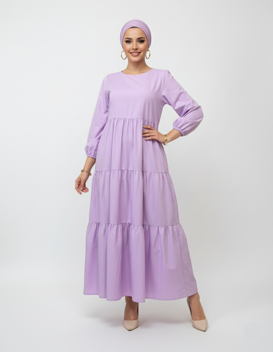 Woman wearing a long lilac dress with a matching headscarf on a white background
