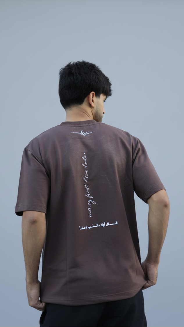 Man wearing a brown t-shirt with text on the back, standing against a plain background