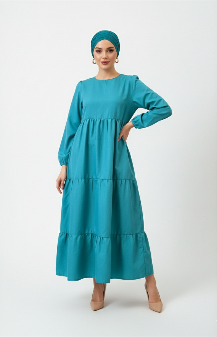 Woman wearing a teal dress and headscarf on a white background
