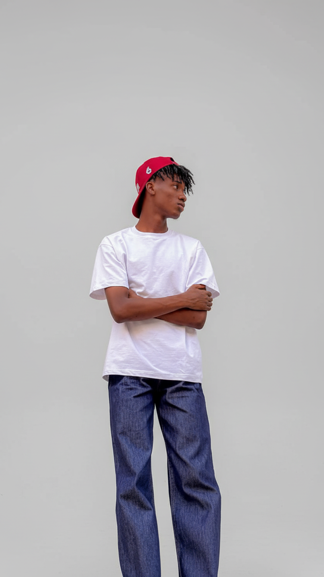 Person wearing a white t-shirt, blue jeans, and a red cap on a gray background
