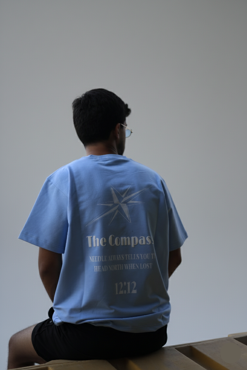 Person wearing a blue t-shirt with text and graphics, sitting against a plain background