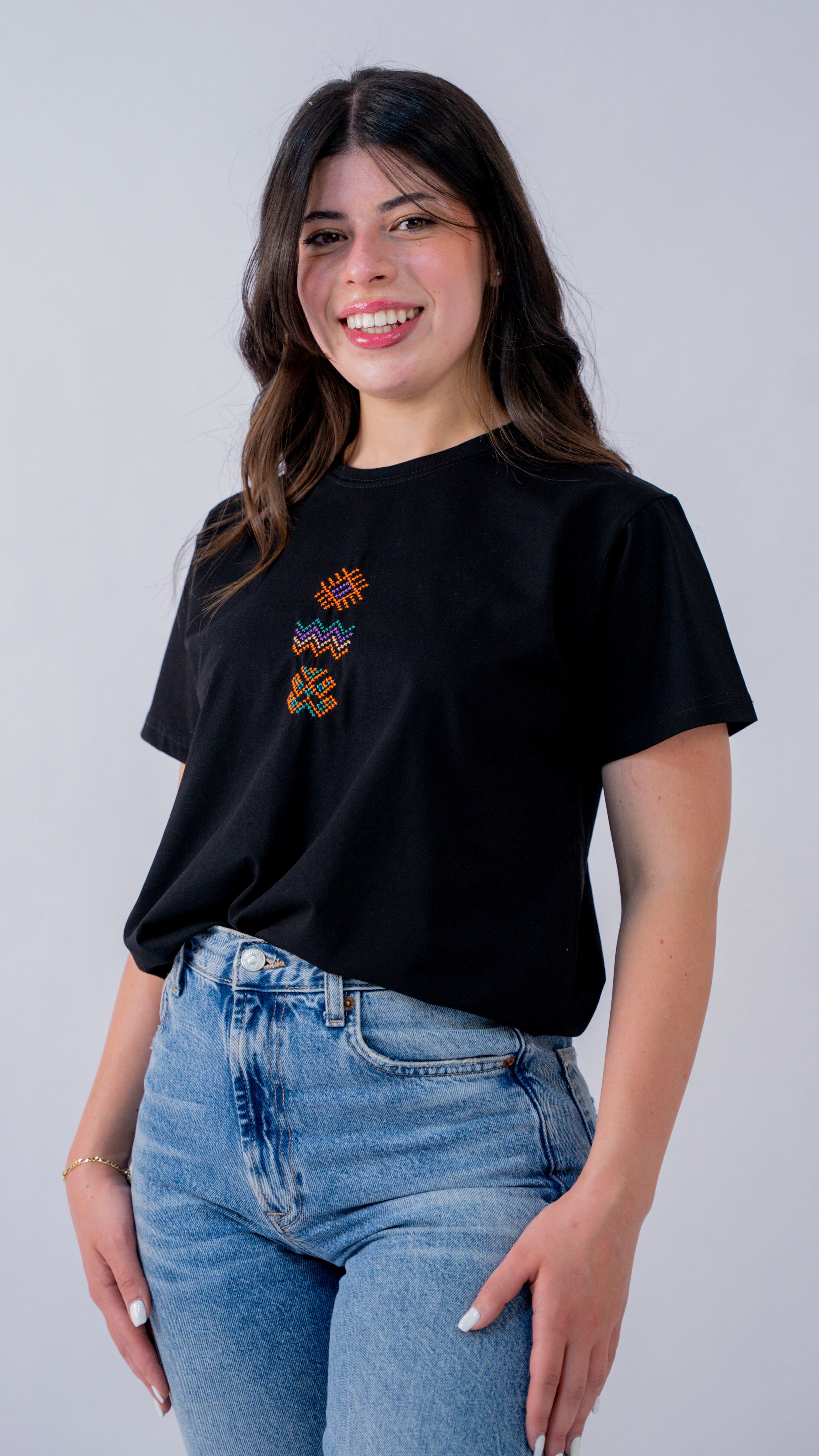 Woman wearing a black t-shirt with a colorful design on a plain background