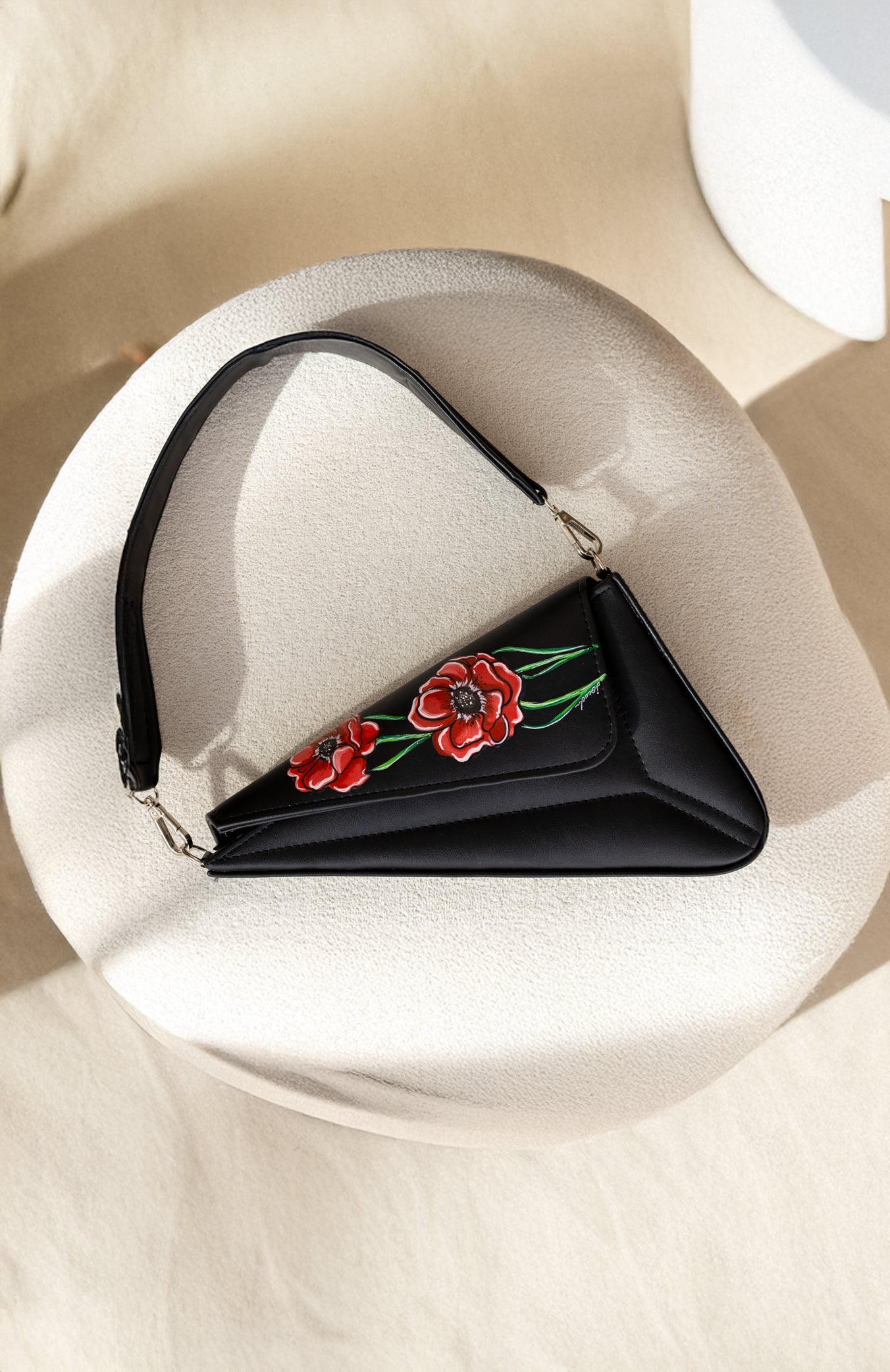 Black handbag with floral embroidery on a white surface