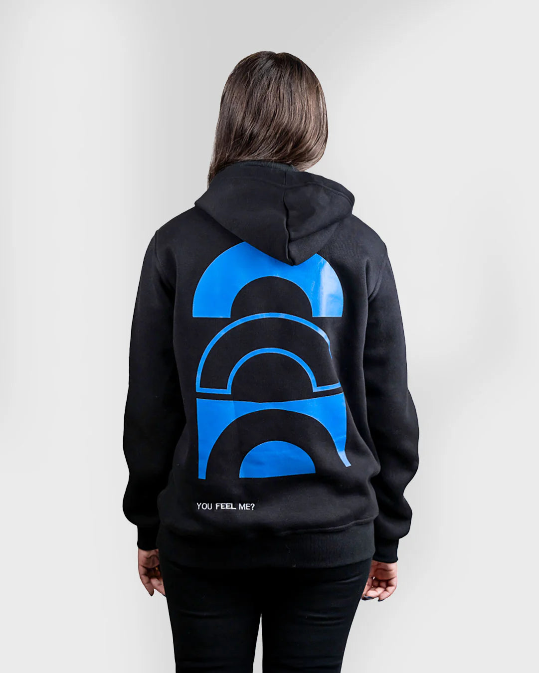 Person wearing a black hoodie with a blue graphic on the back against a white background