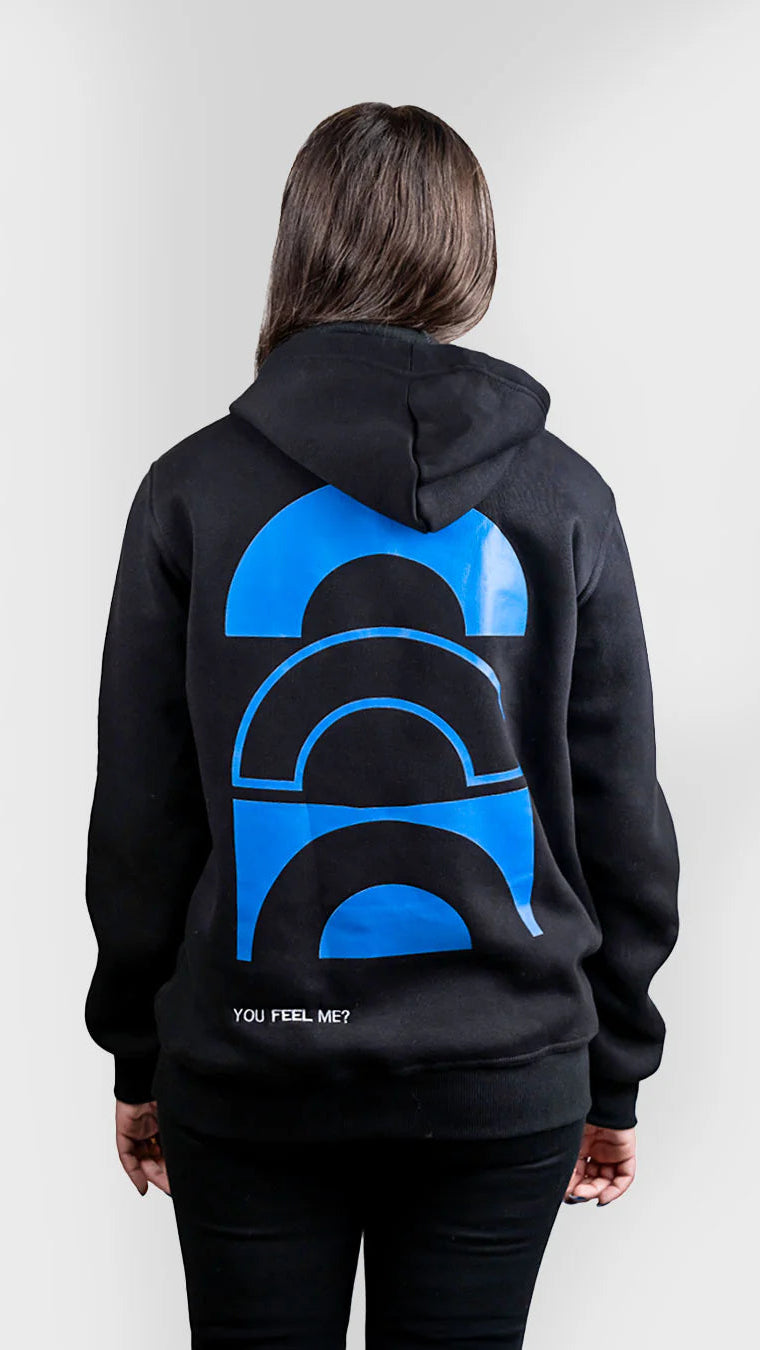 Person wearing a black hoodie with a blue graphic on the back against a white background