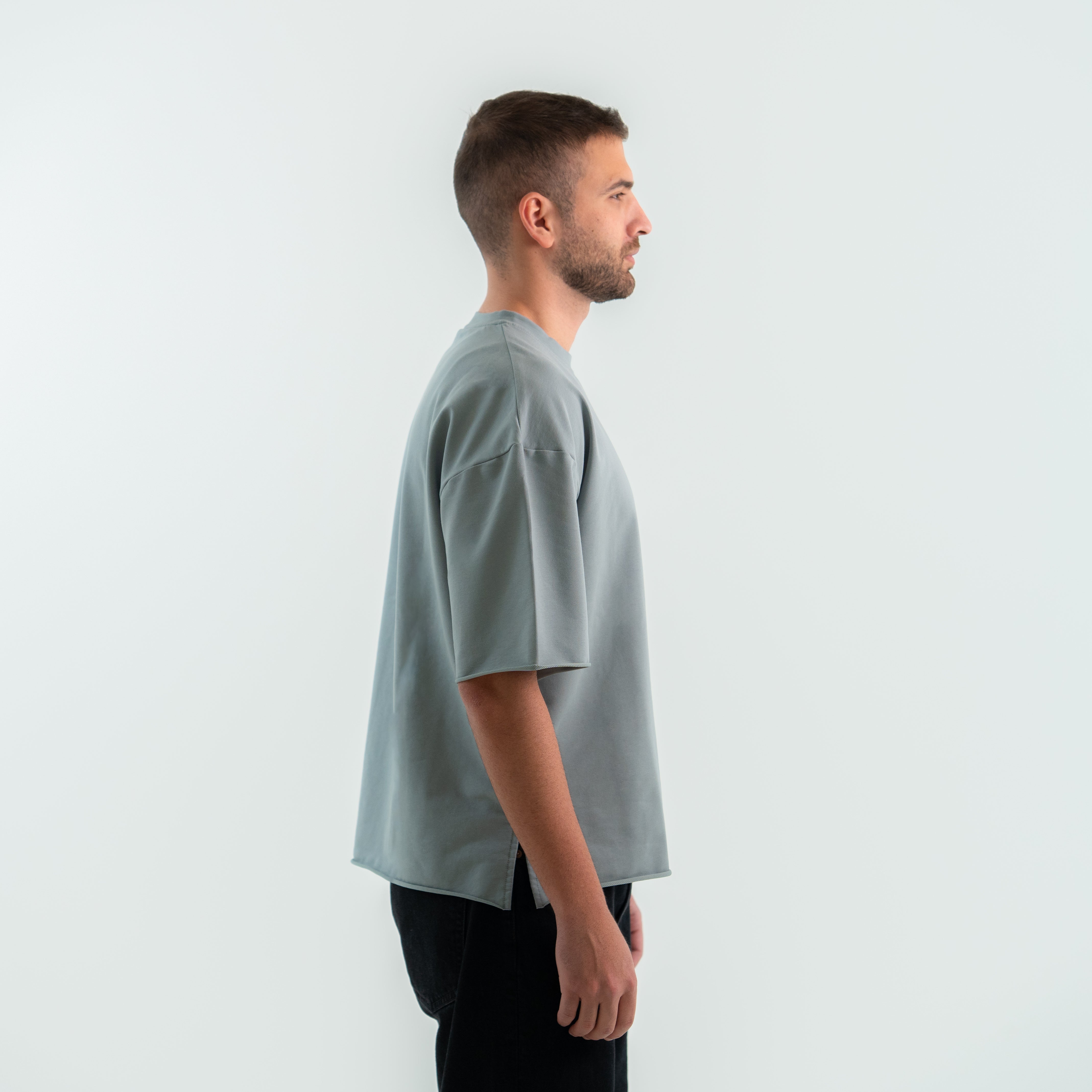 Man wearing a light gray t-shirt against a white background