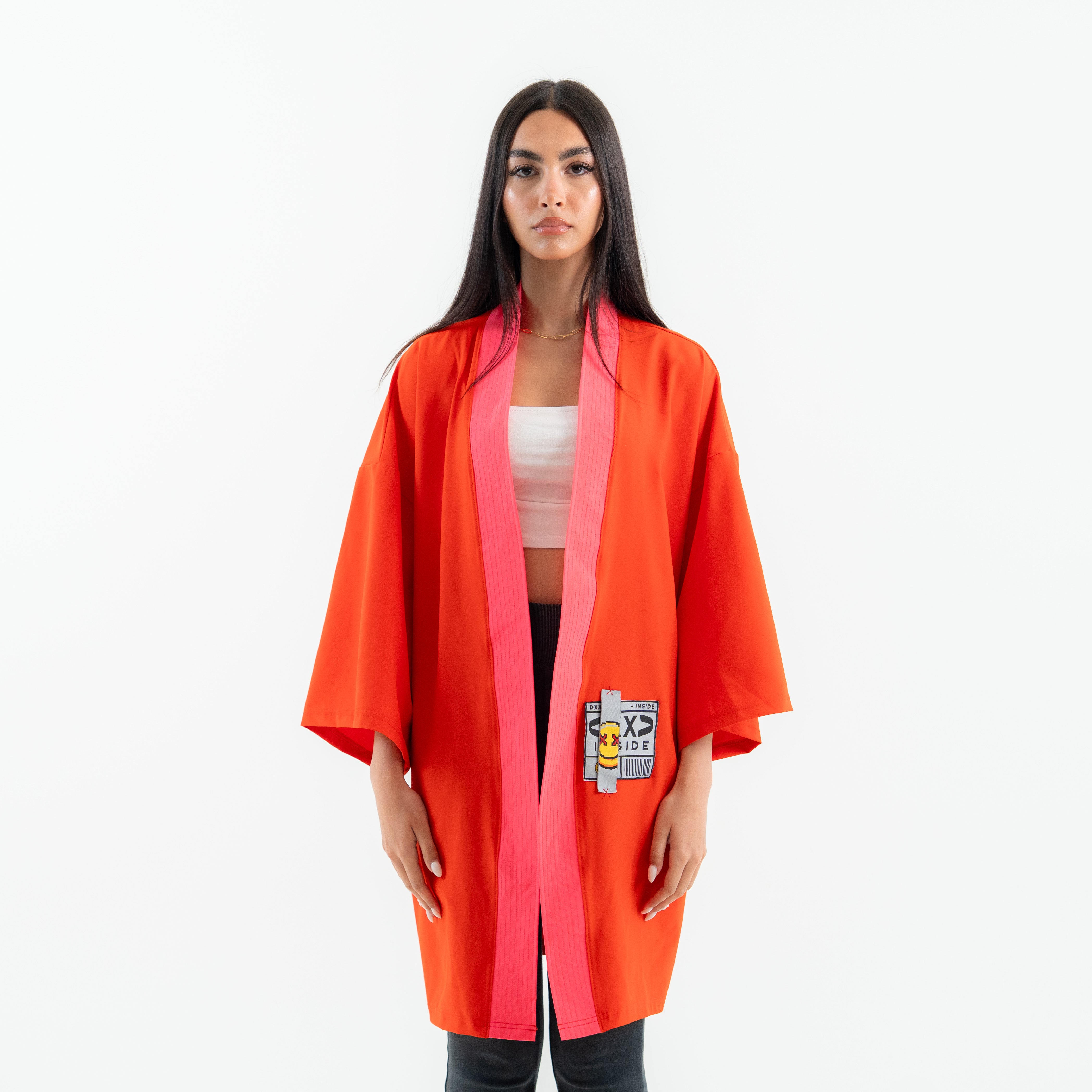 Woman wearing a bright orange kimono-style robe with a patch on a white background