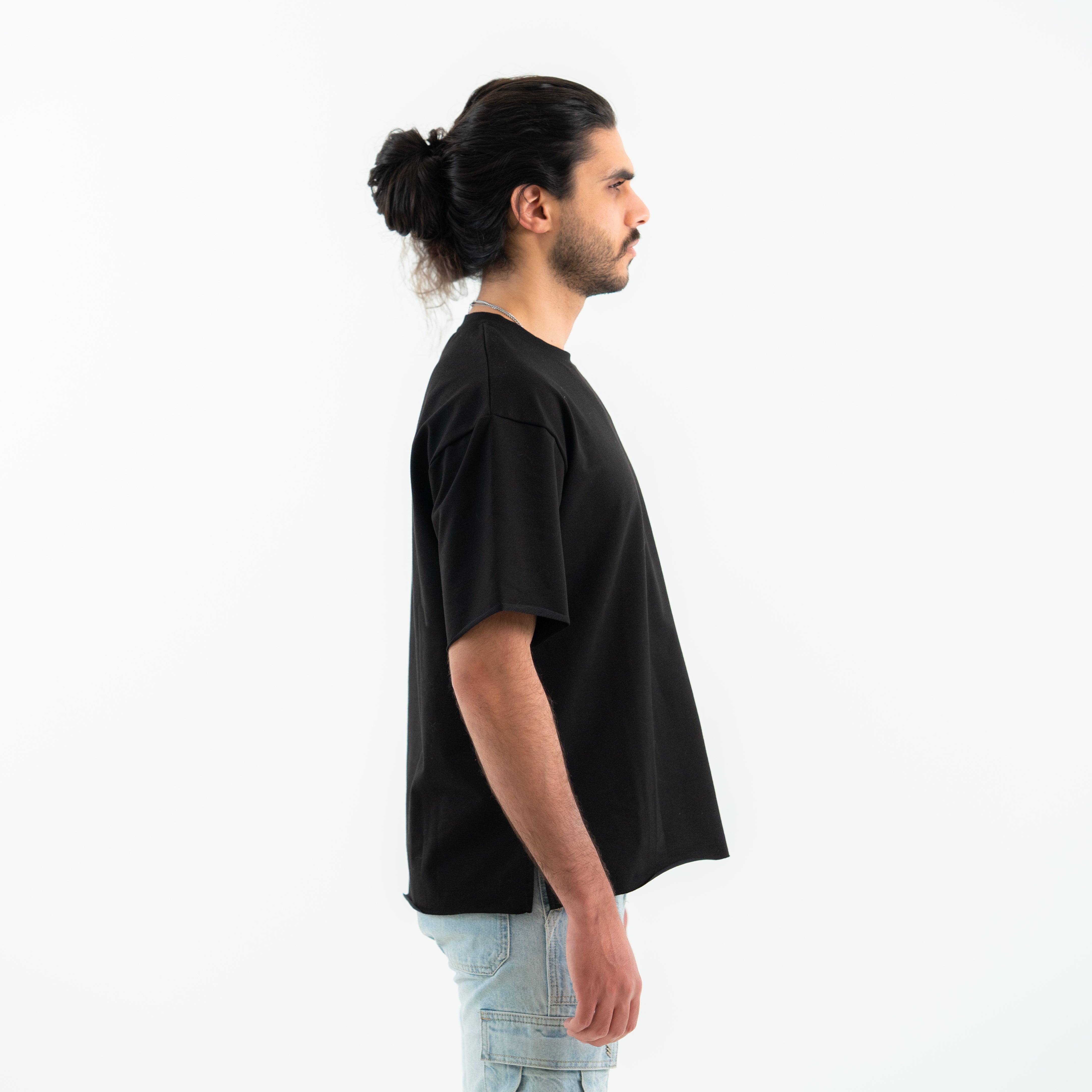 Man wearing a black t-shirt and light blue jeans on a white background