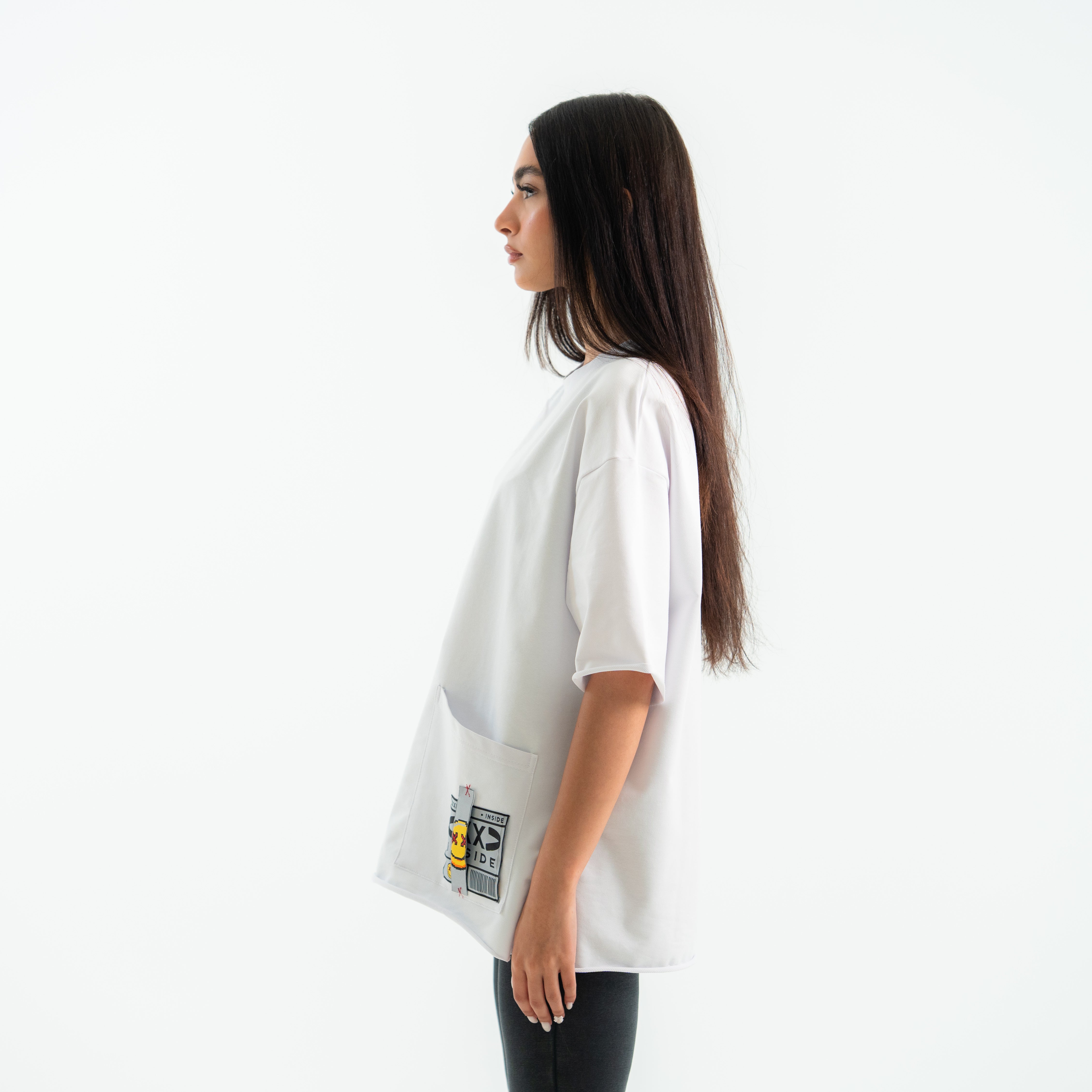 Woman wearing a white oversized t-shirt with graphic designs on a white background