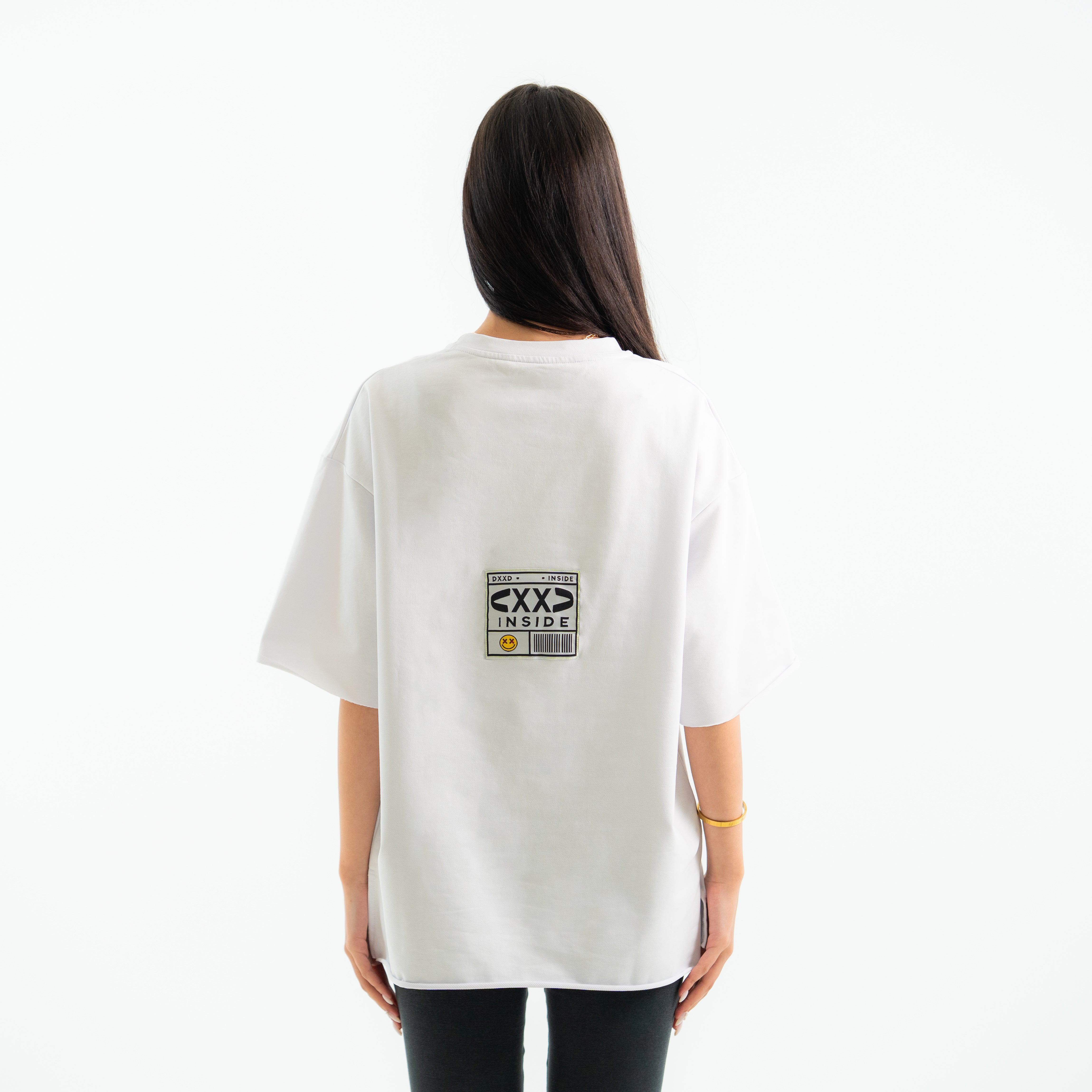 Person wearing a white t-shirt with a graphic design on the back against a white background