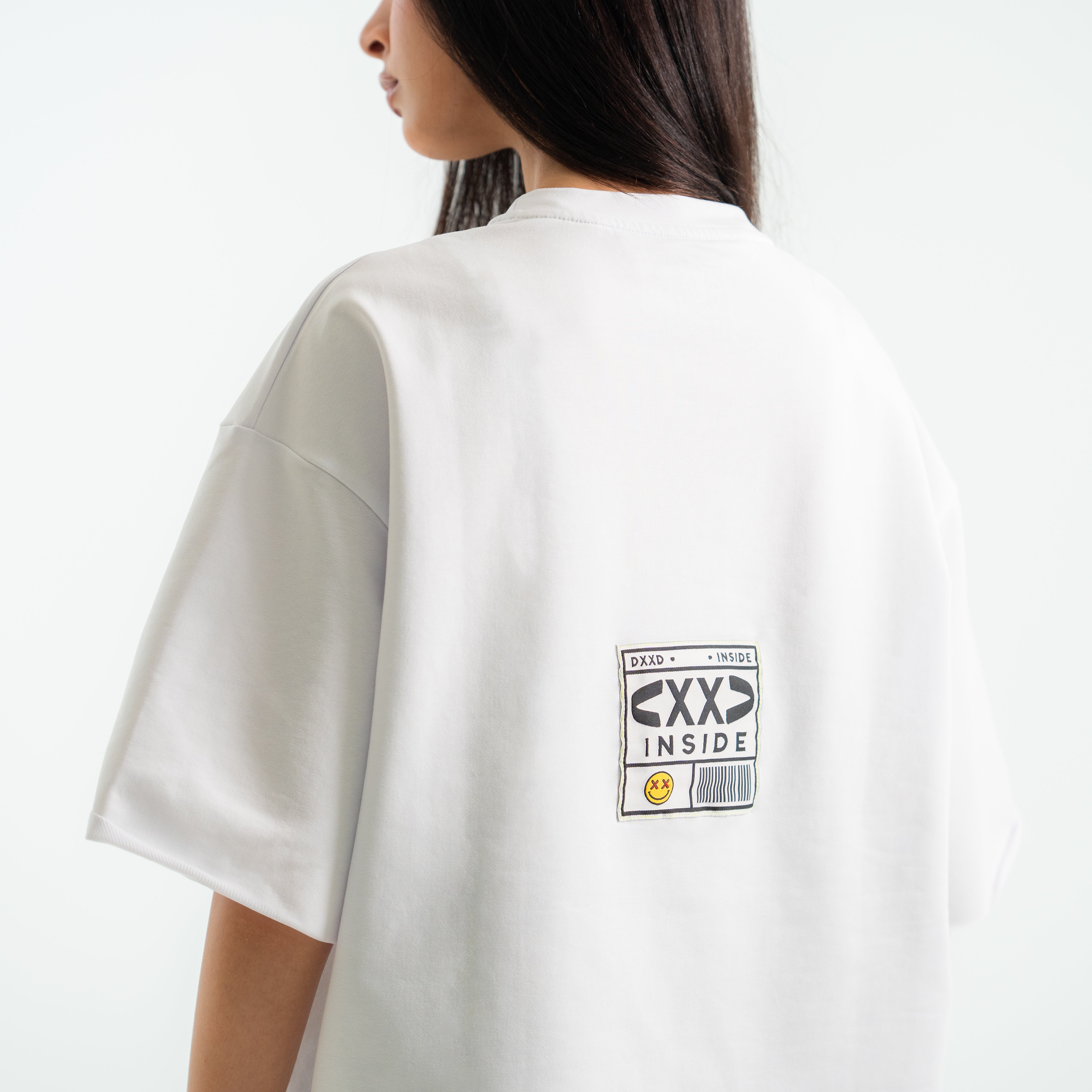 White t-shirt with a graphic design on the back, worn by a person.