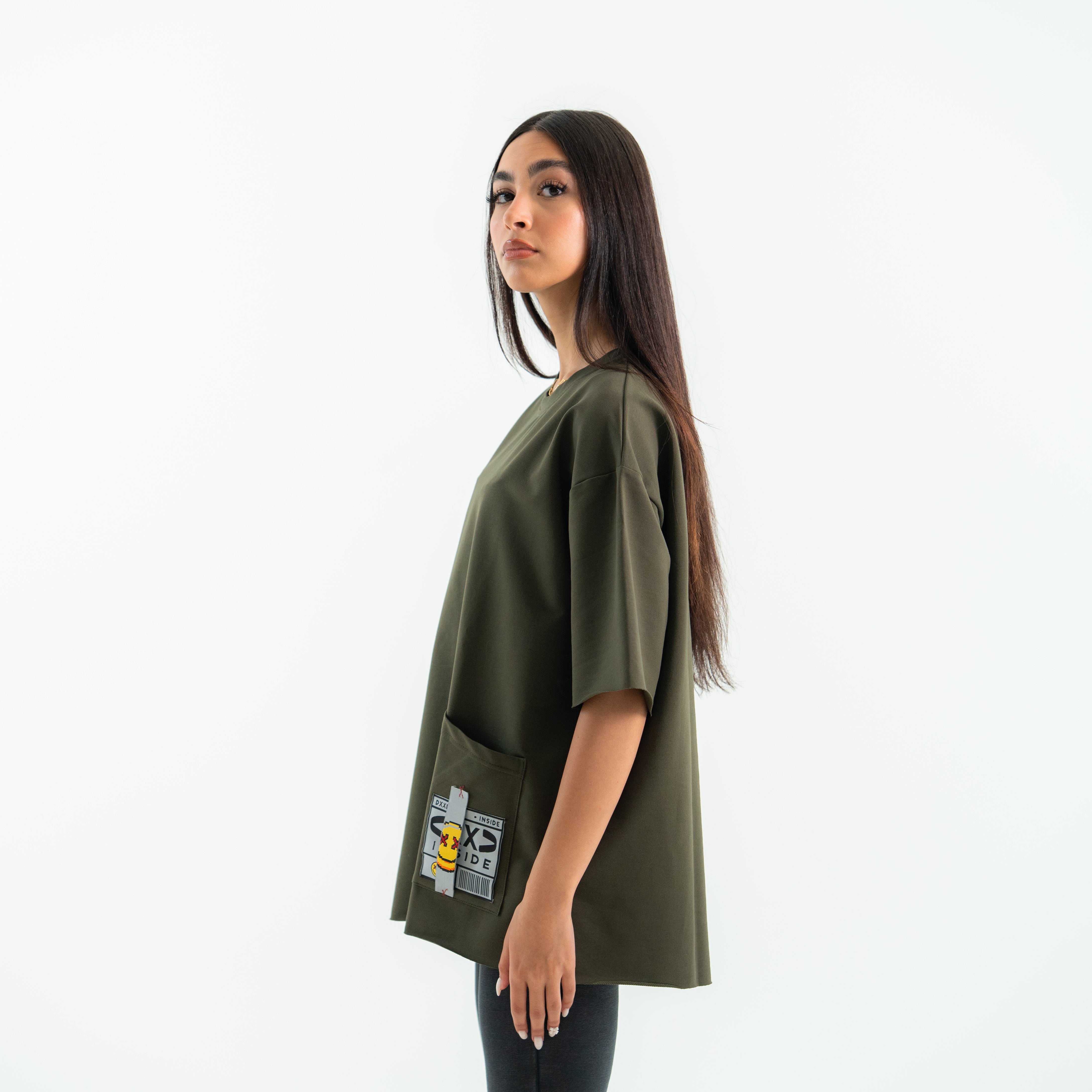 Woman wearing a green oversized t-shirt with a graphic design on a white background