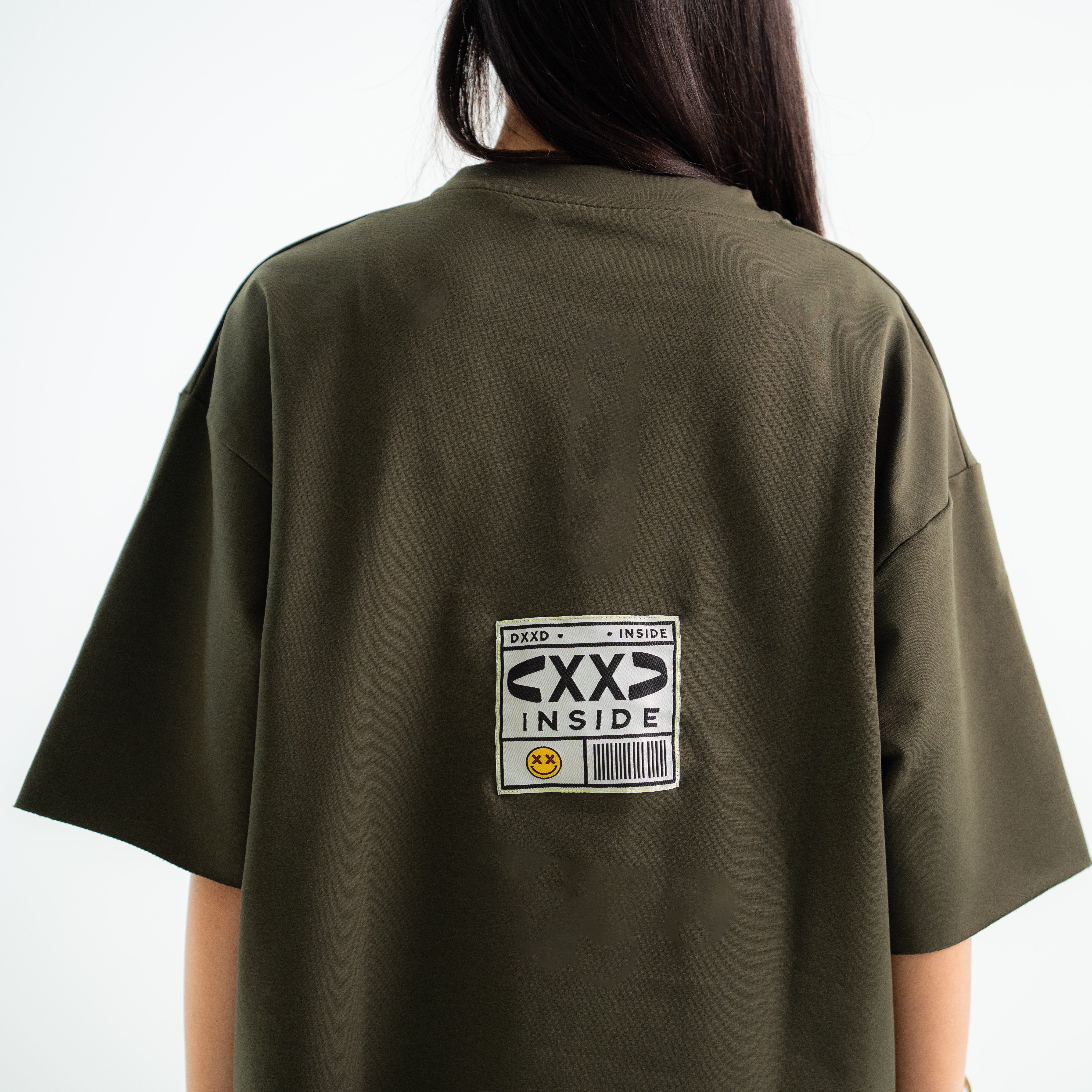 Person wearing a green t-shirt with a graphic design on the back against a white background