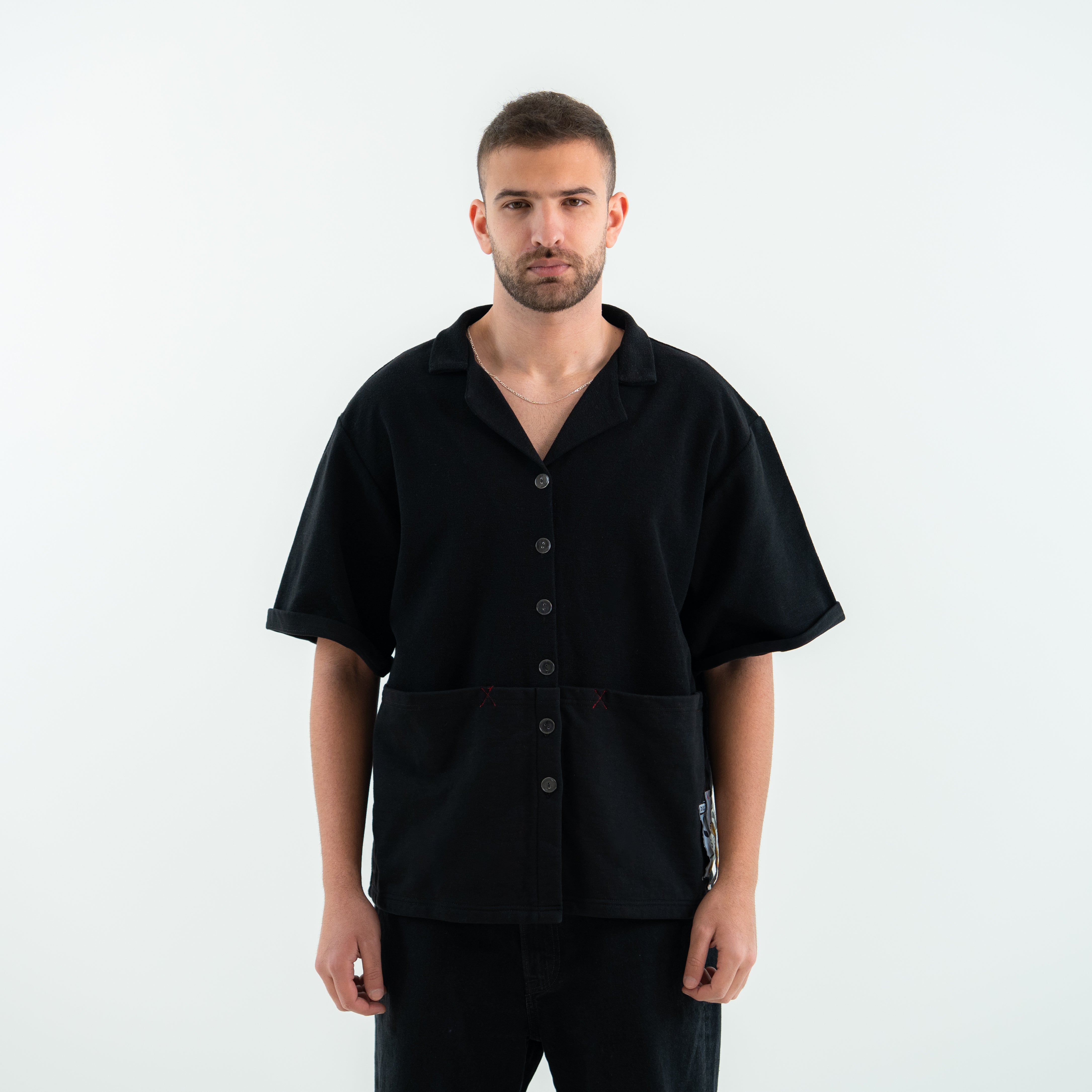 Man wearing a black short-sleeve button-up shirt on a white background