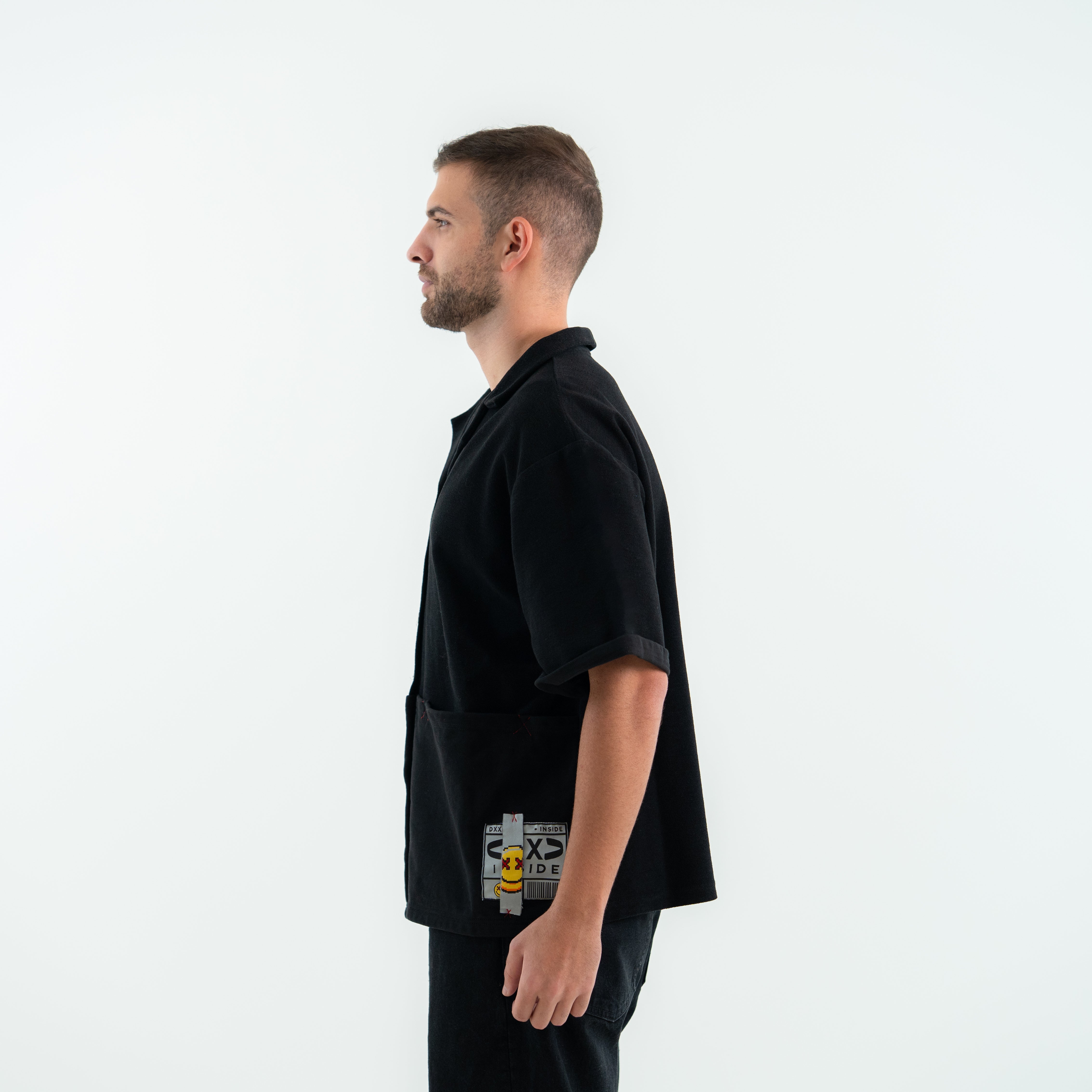 Man wearing a black t-shirt with a logo on the chest against a white background