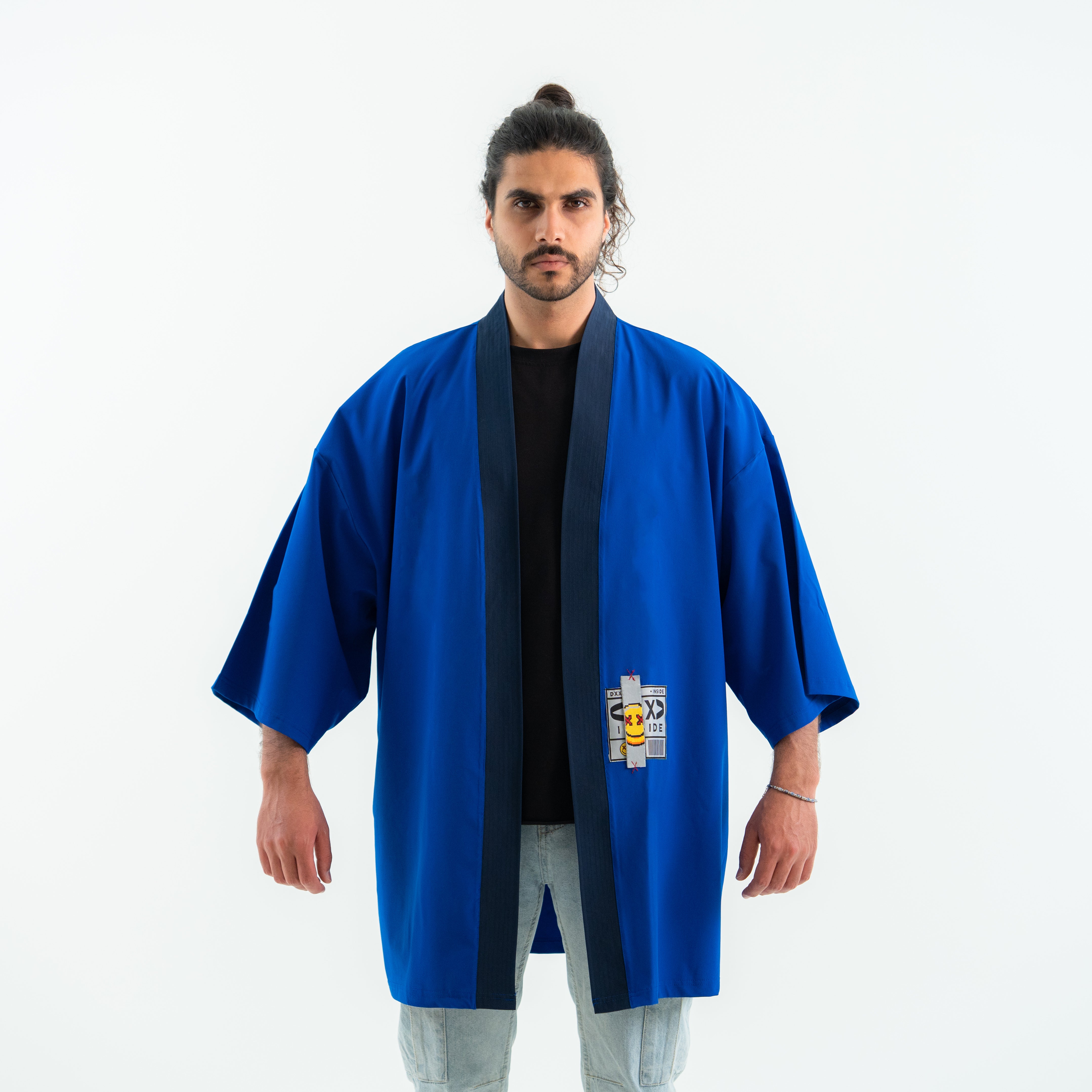 Man wearing a blue martial arts robe with a logo on a white background