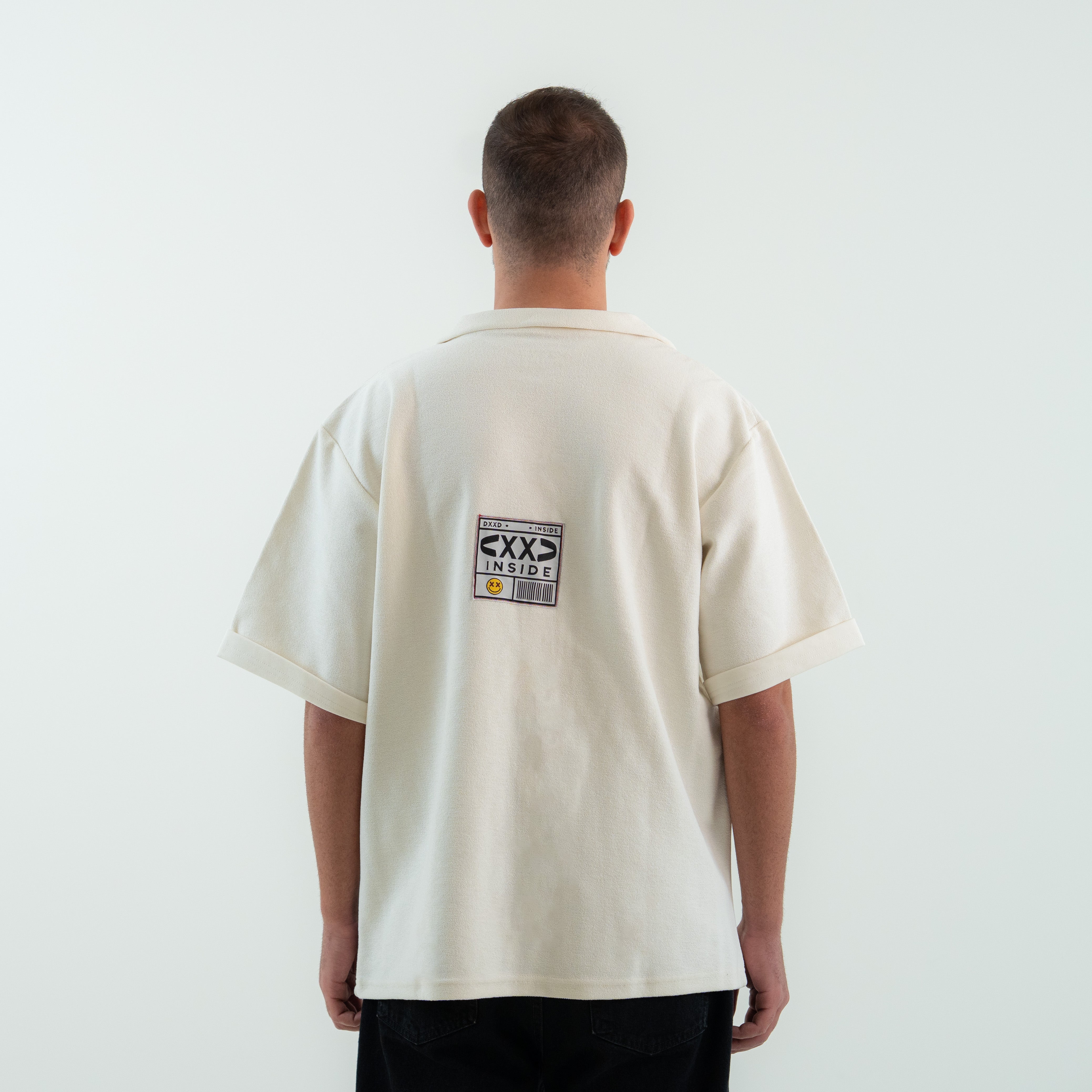 Person wearing a white t-shirt with text on the back against a plain background