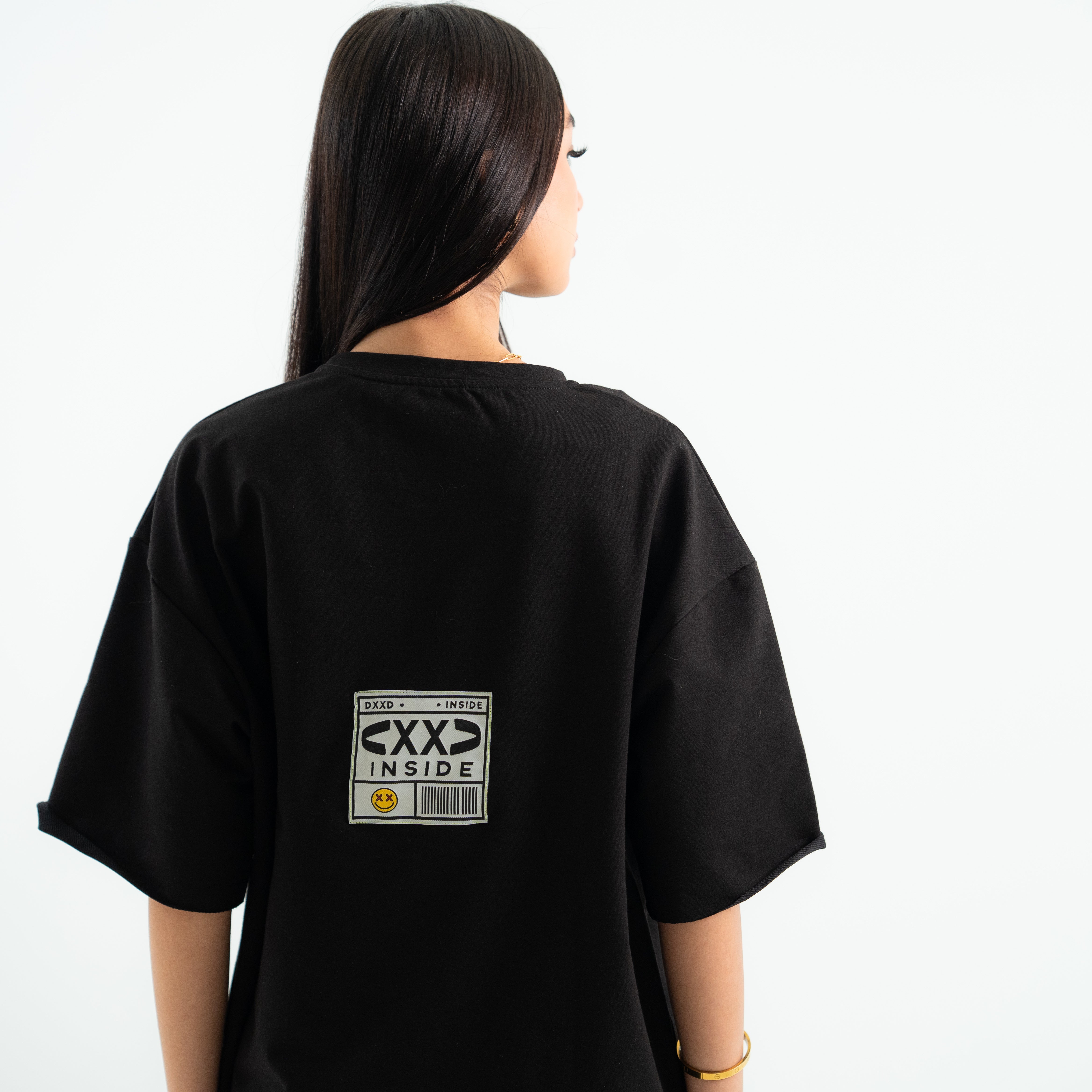Person wearing a black t-shirt with a graphic on the back against a white background