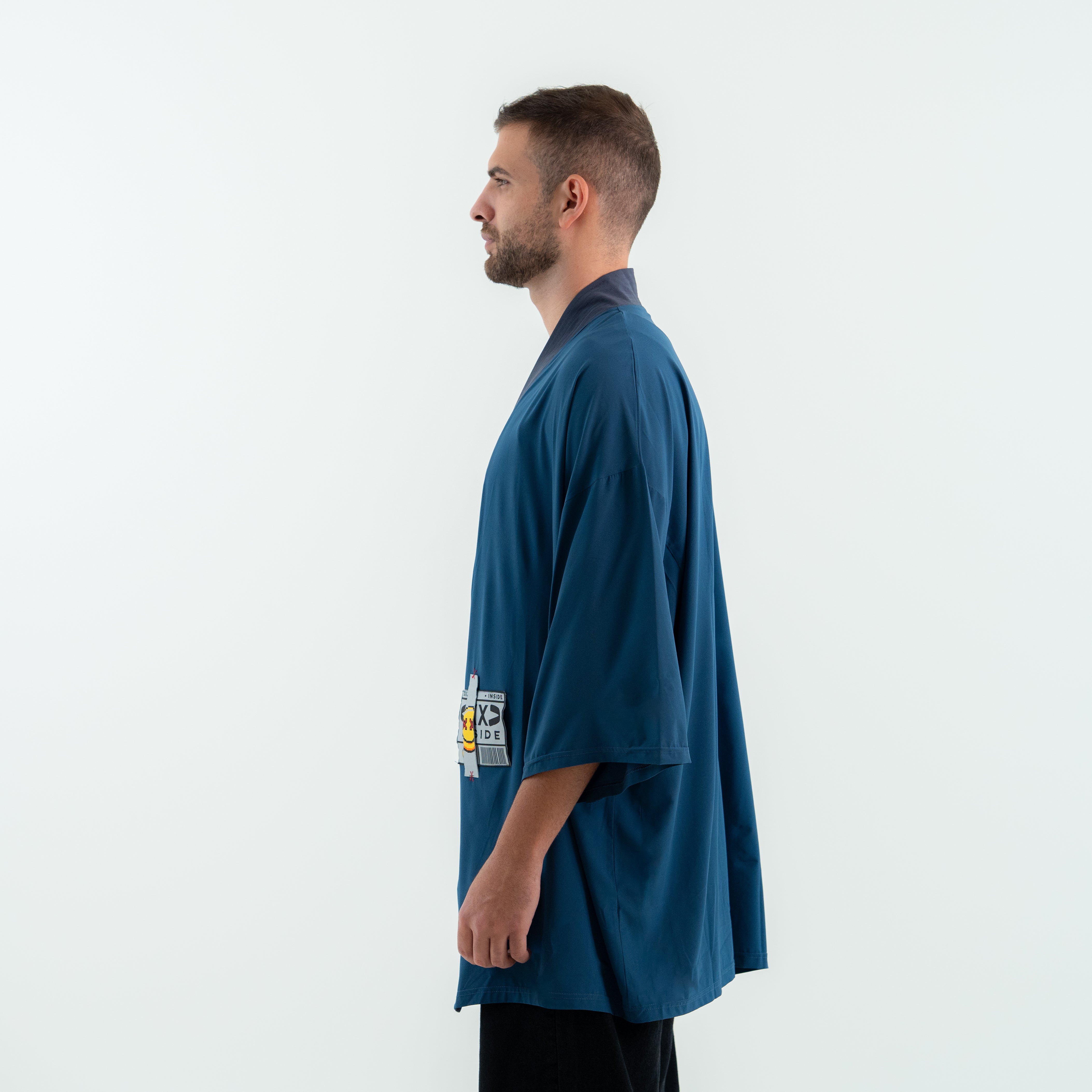 Man wearing a blue oversized shirt with graphic designs on a white background