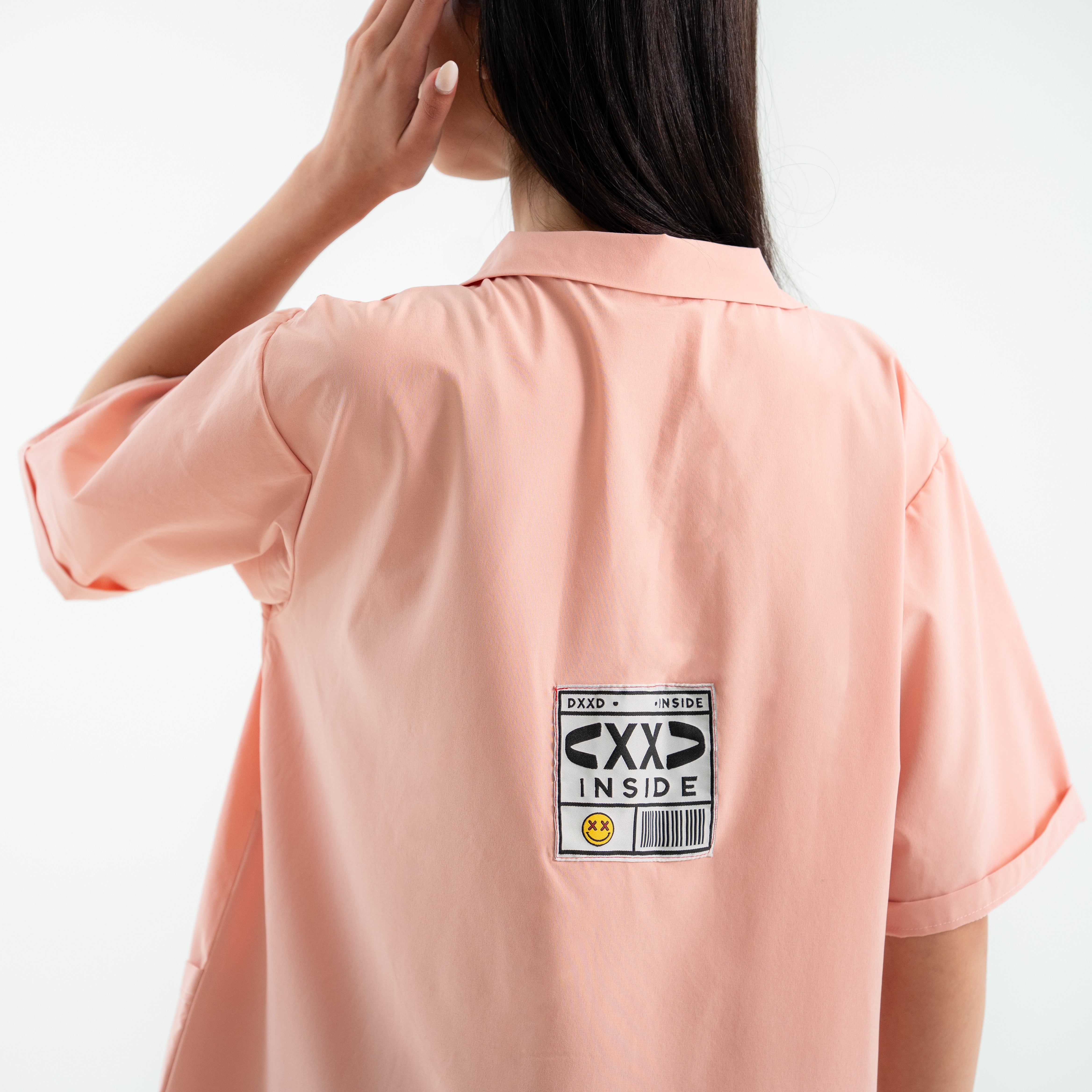 Person wearing a light pink shirt with a label on the back
