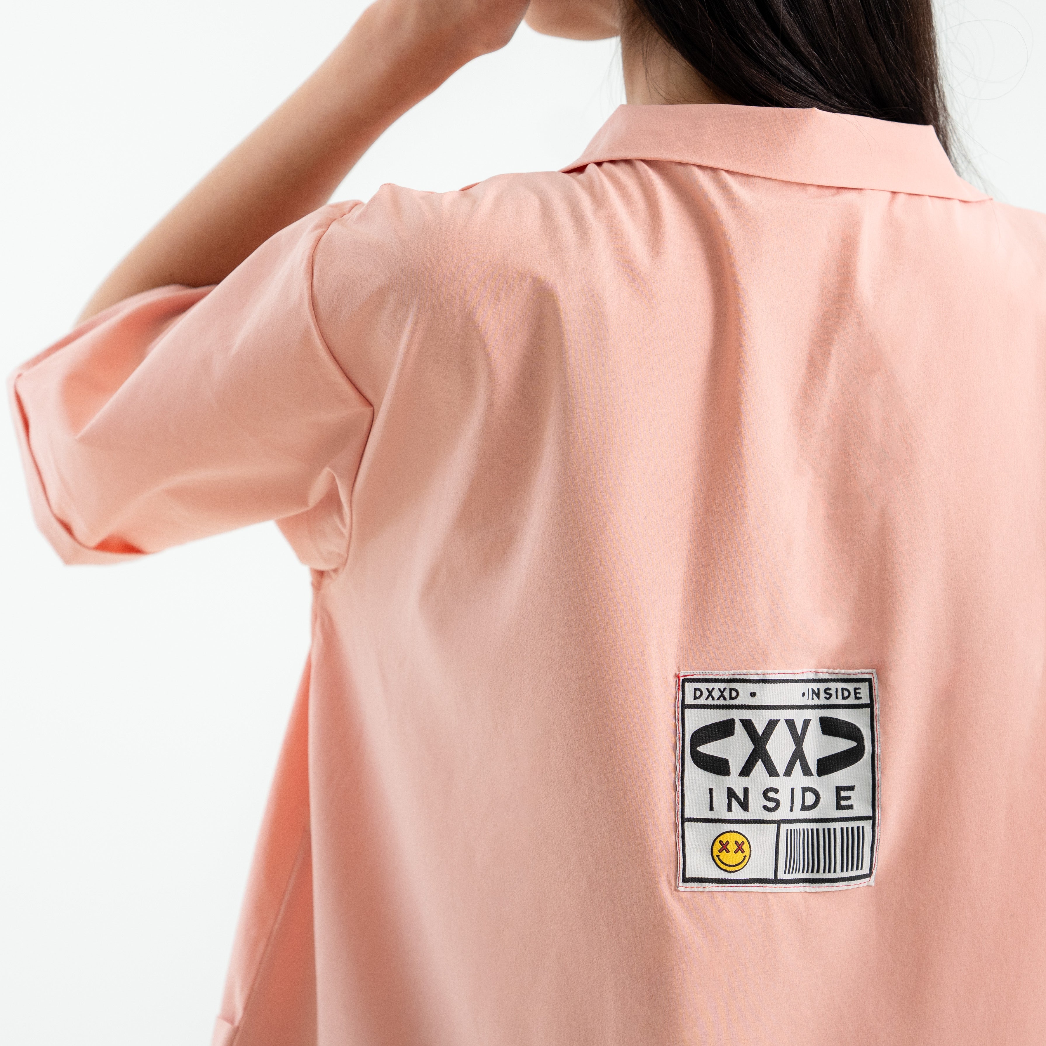 Person wearing a light pink shirt with a label on the chest area.