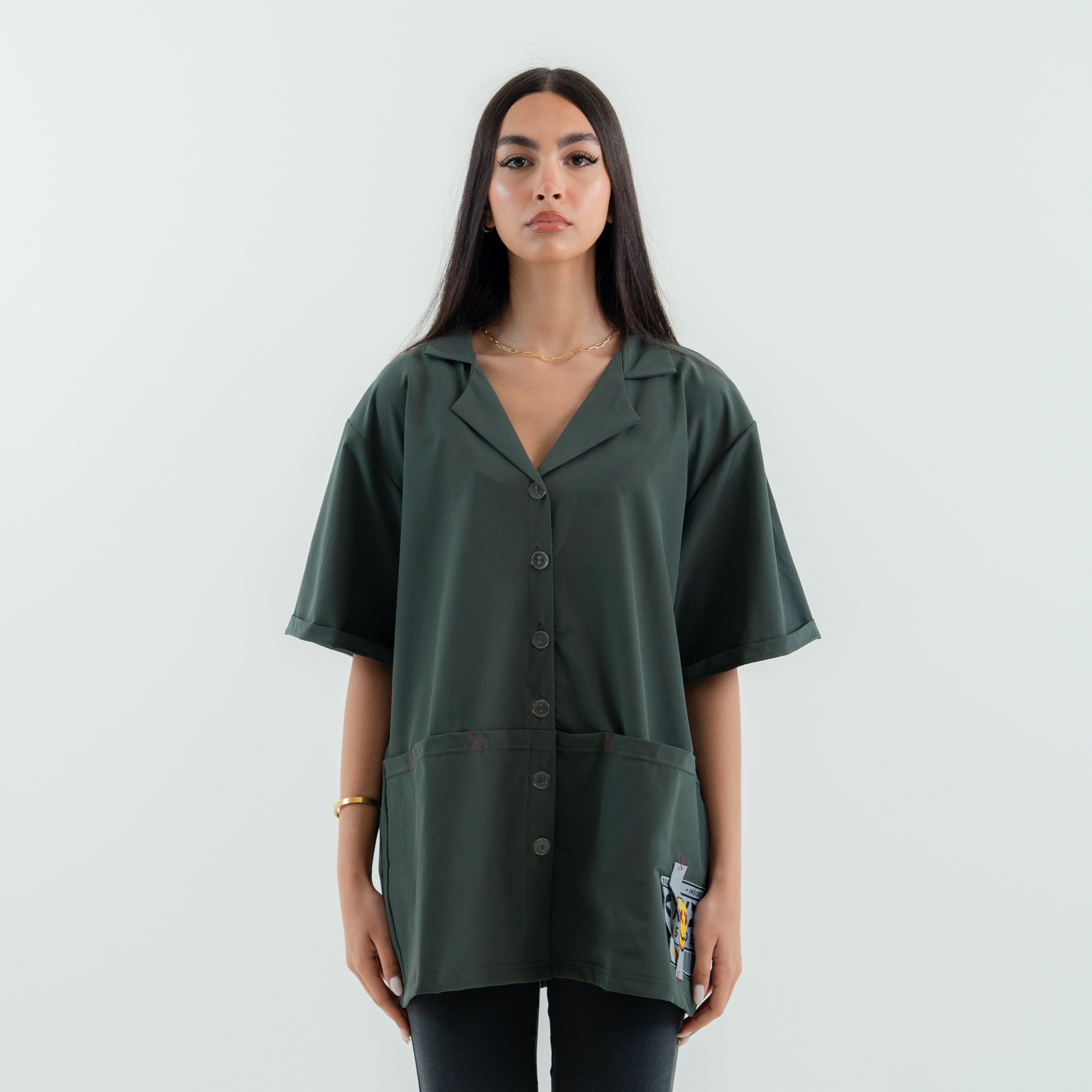 Woman wearing a green oversized shirt with button details on a white background