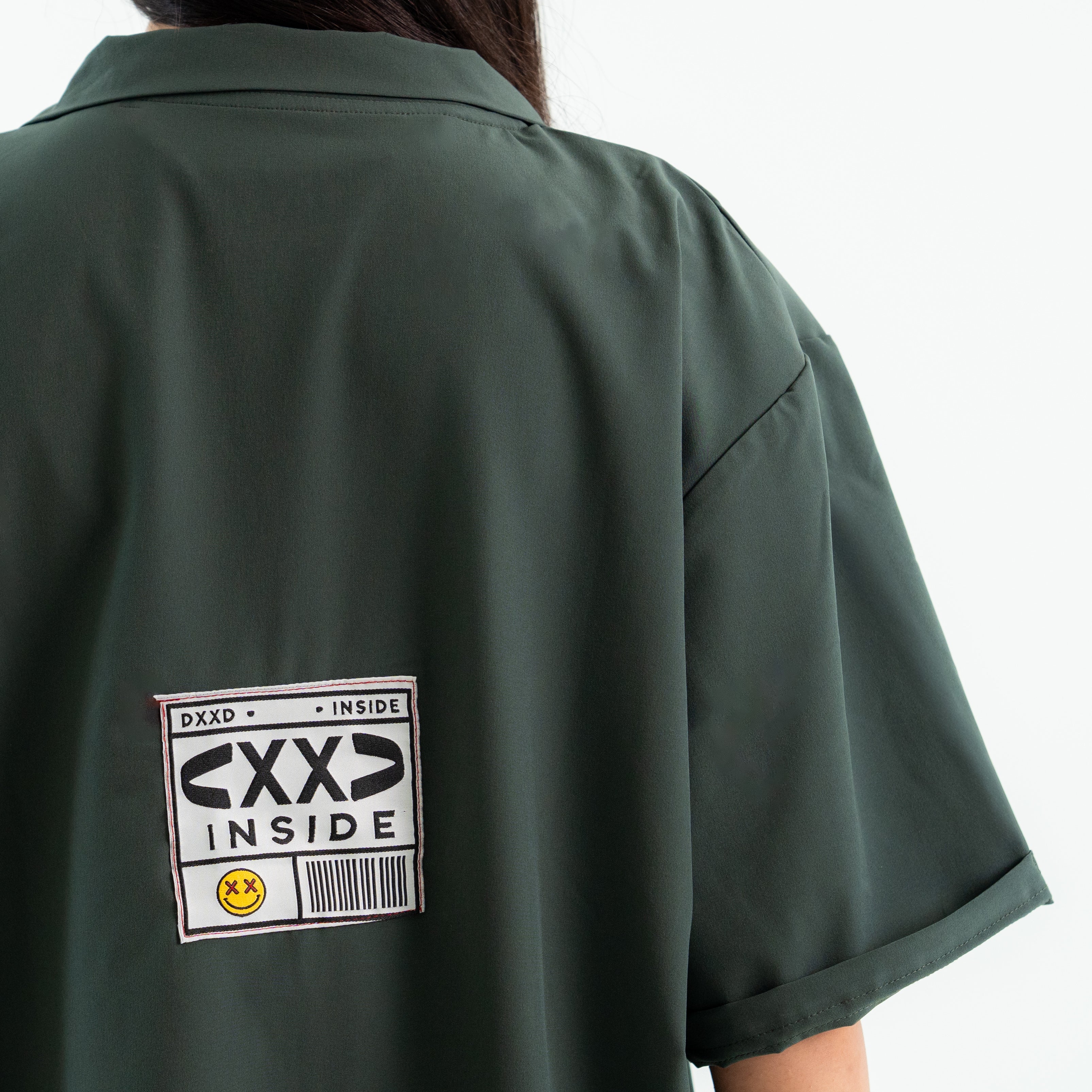 Green shirt with 'CXXD INSIDE' label on the back against a white background