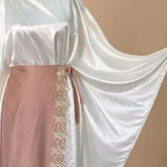 White garment with a pink section featuring floral embroidery on a beige background
