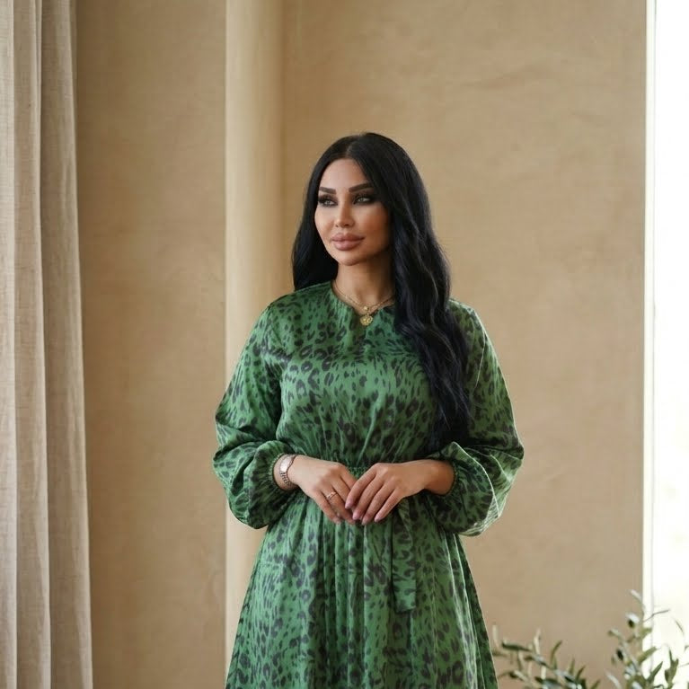 Woman wearing a green dress with a pattern against a beige curtain background