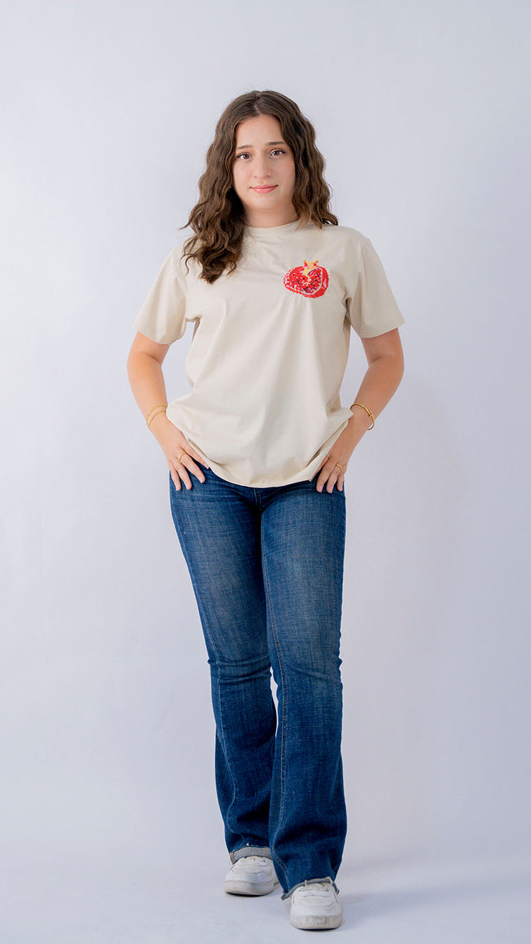Woman wearing a beige t-shirt with a red logo and blue jeans on a white background