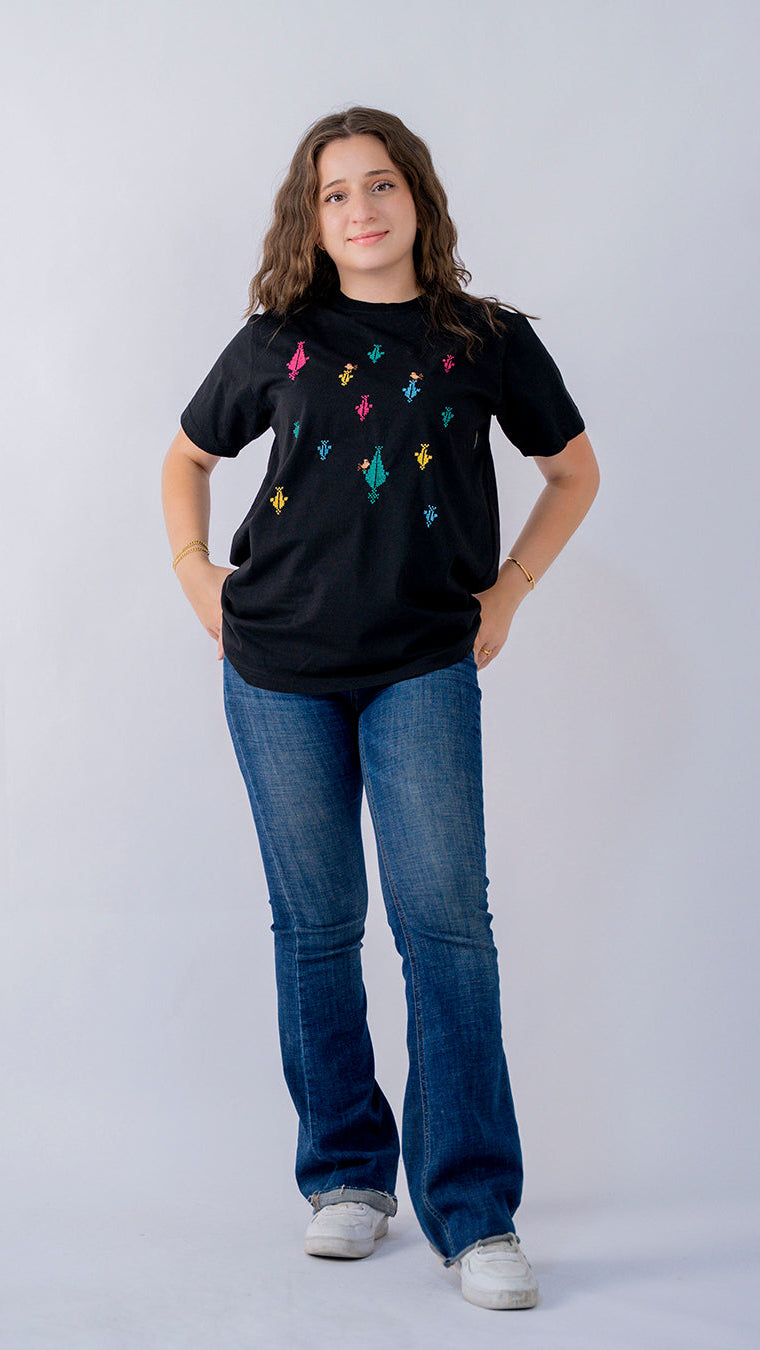 Person wearing a black t-shirt with colorful designs and blue jeans on a white background