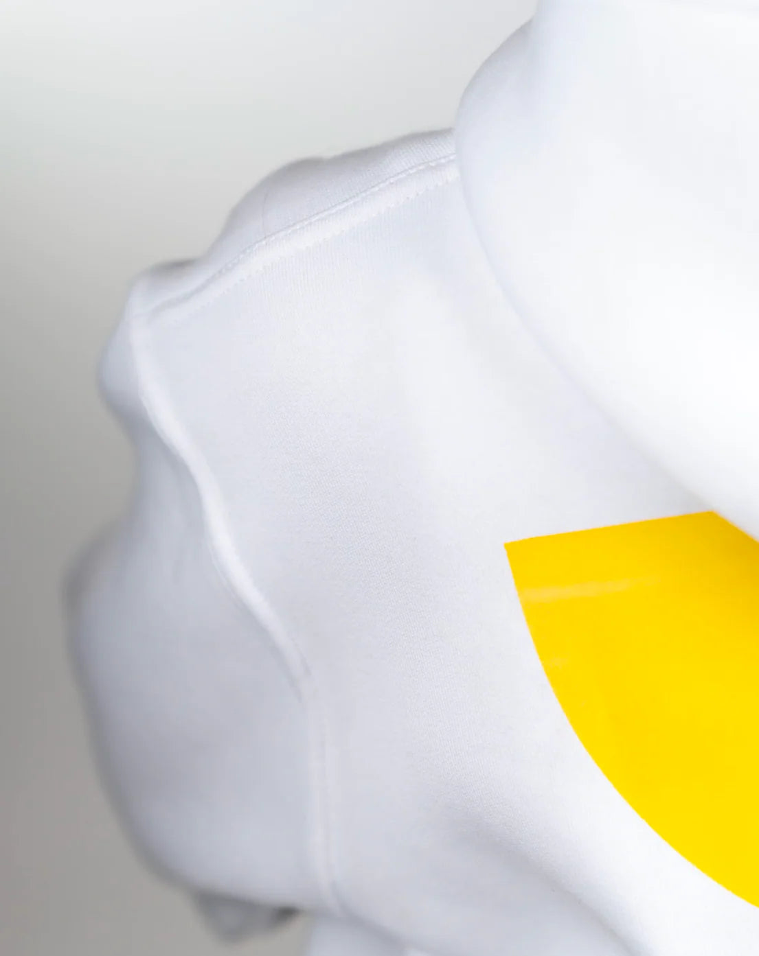 White shirt with a yellow circle design on a plain background