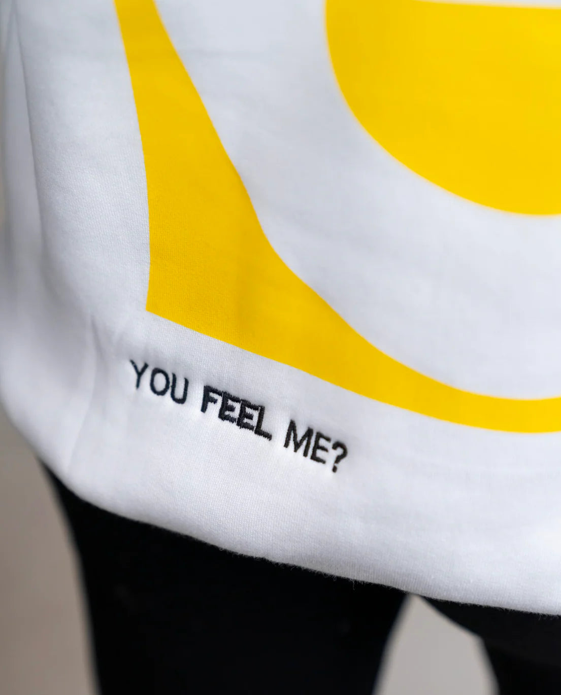 White shirt with yellow circle design and text 'YOU FEEL ME?' on a plain background