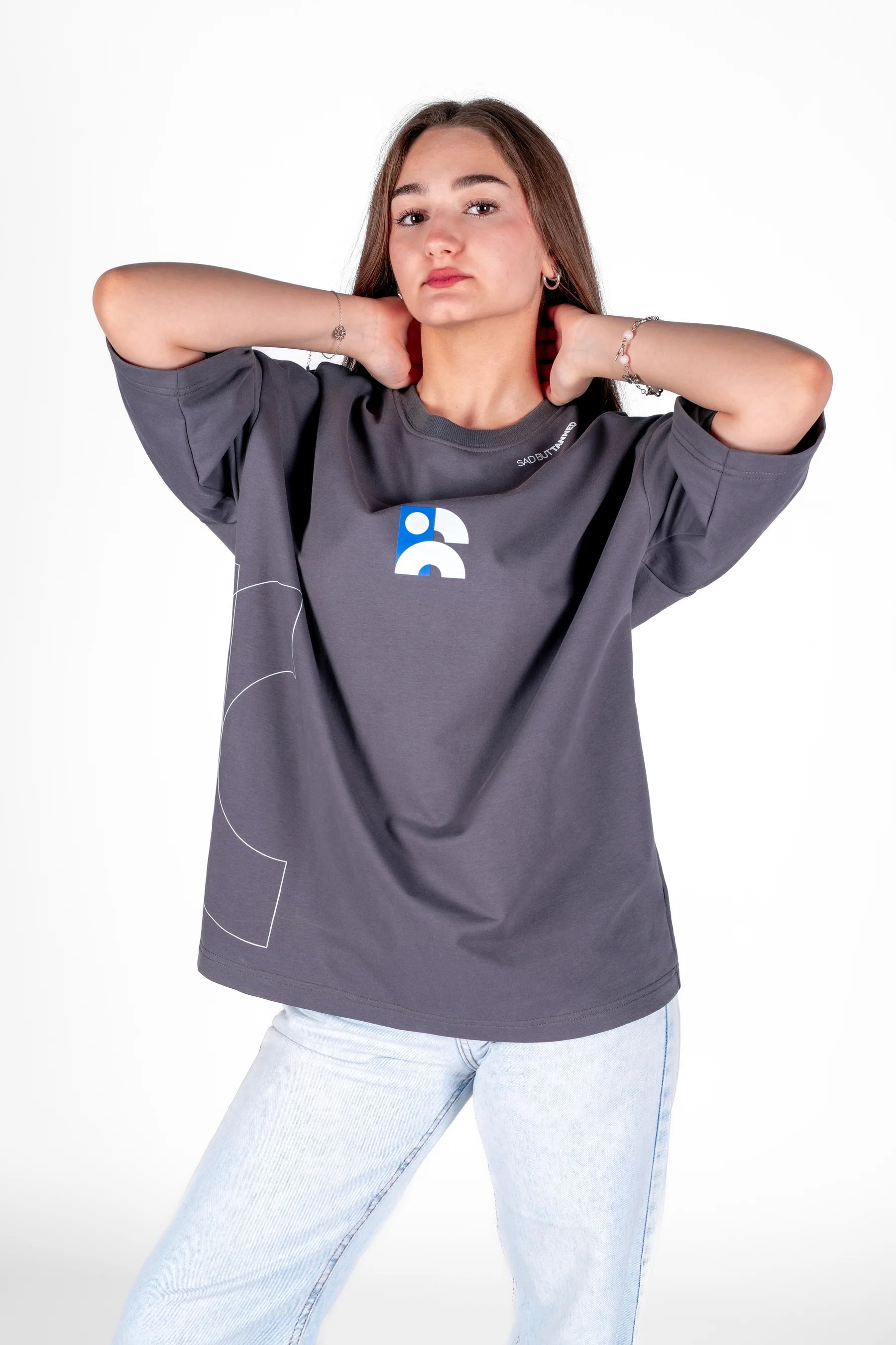 Woman wearing a gray oversized t-shirt with a logo on a white background