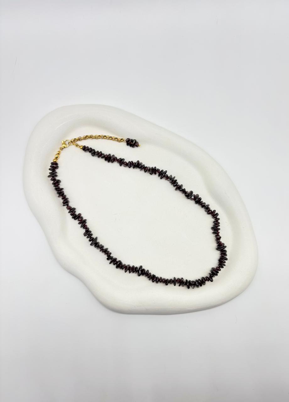 Necklace with black beads on a white dish against a light gray background